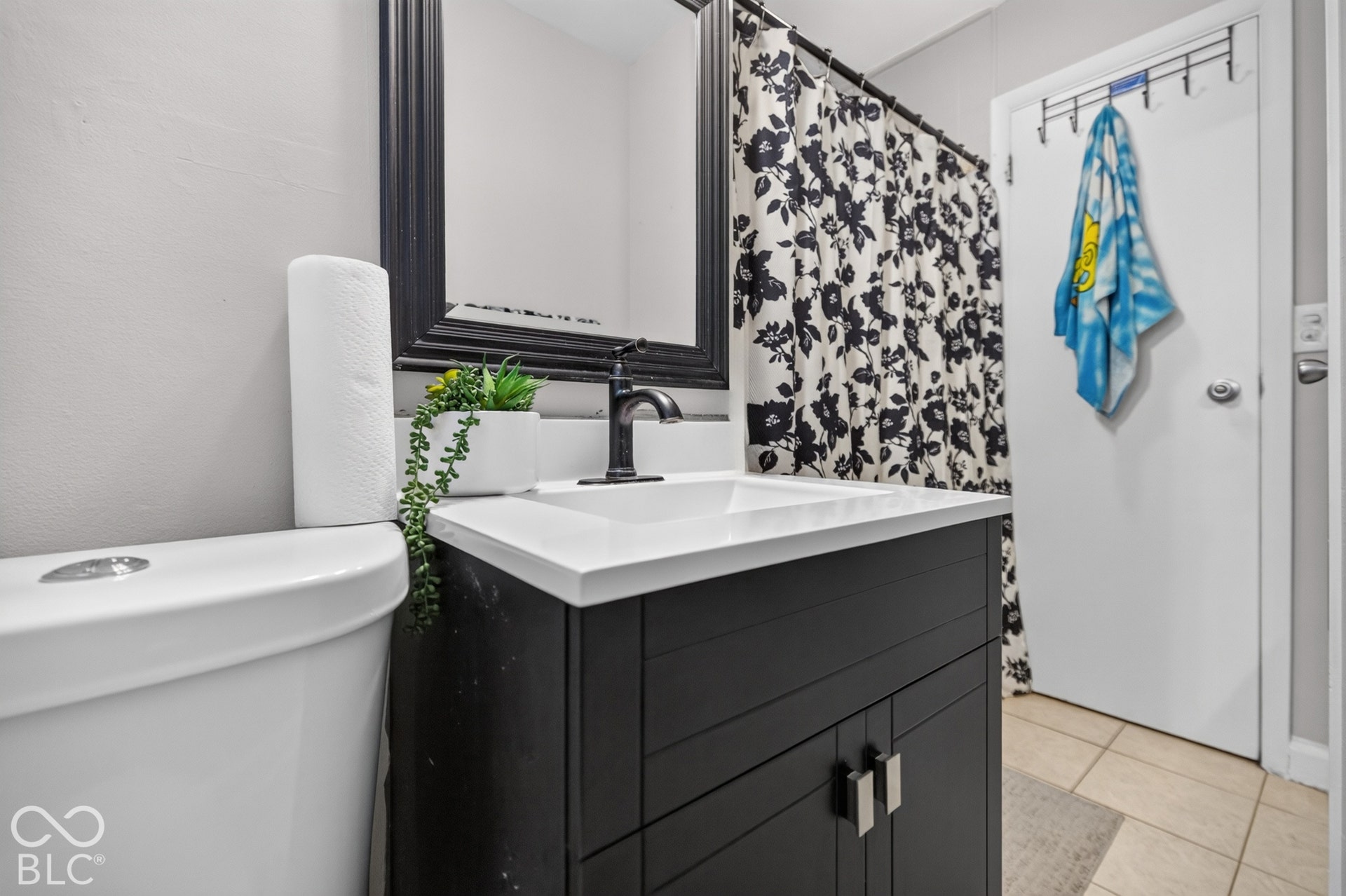 3241 Winton Avenue, Indianapolis, IN 46224 Bathroom featuring a dark wood-finish vanity with a white countertop and integrated sink, matte black faucet, and a framed mirror