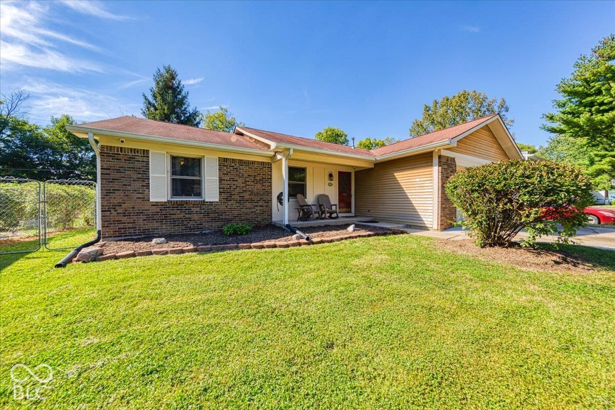 Brick and siding exterior with a covered entry, attached garage, and landscaped front yard