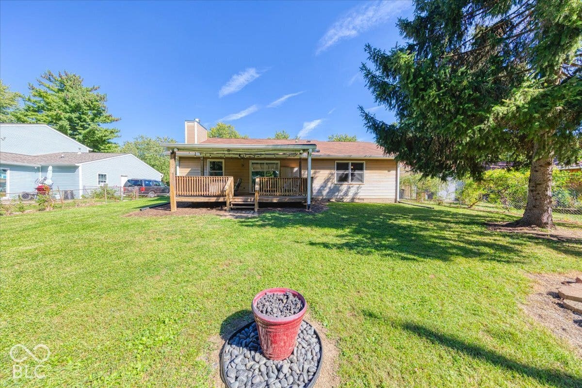 Expansive backyard featuring a large covered wooden deck with an established evergreen tree. Storage shed and fire pit not shown.