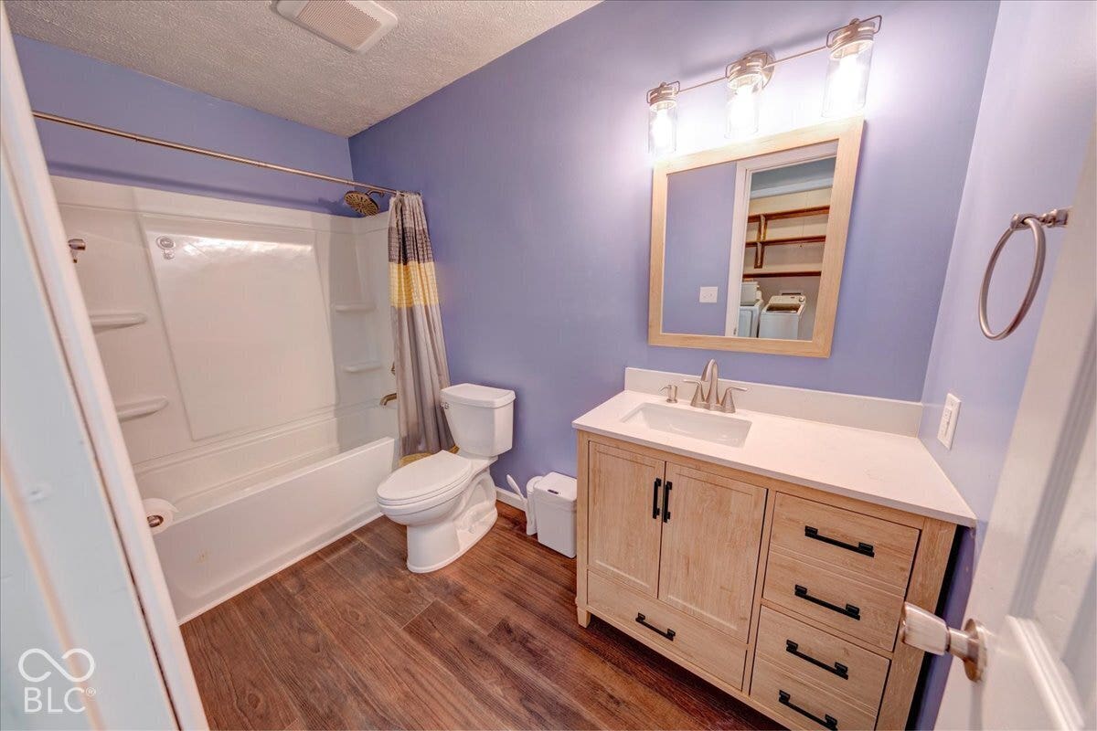 Hallway bathroom featuring vanity with quartz countertop, framed mirror with integrated lighting, and tub/shower combo.