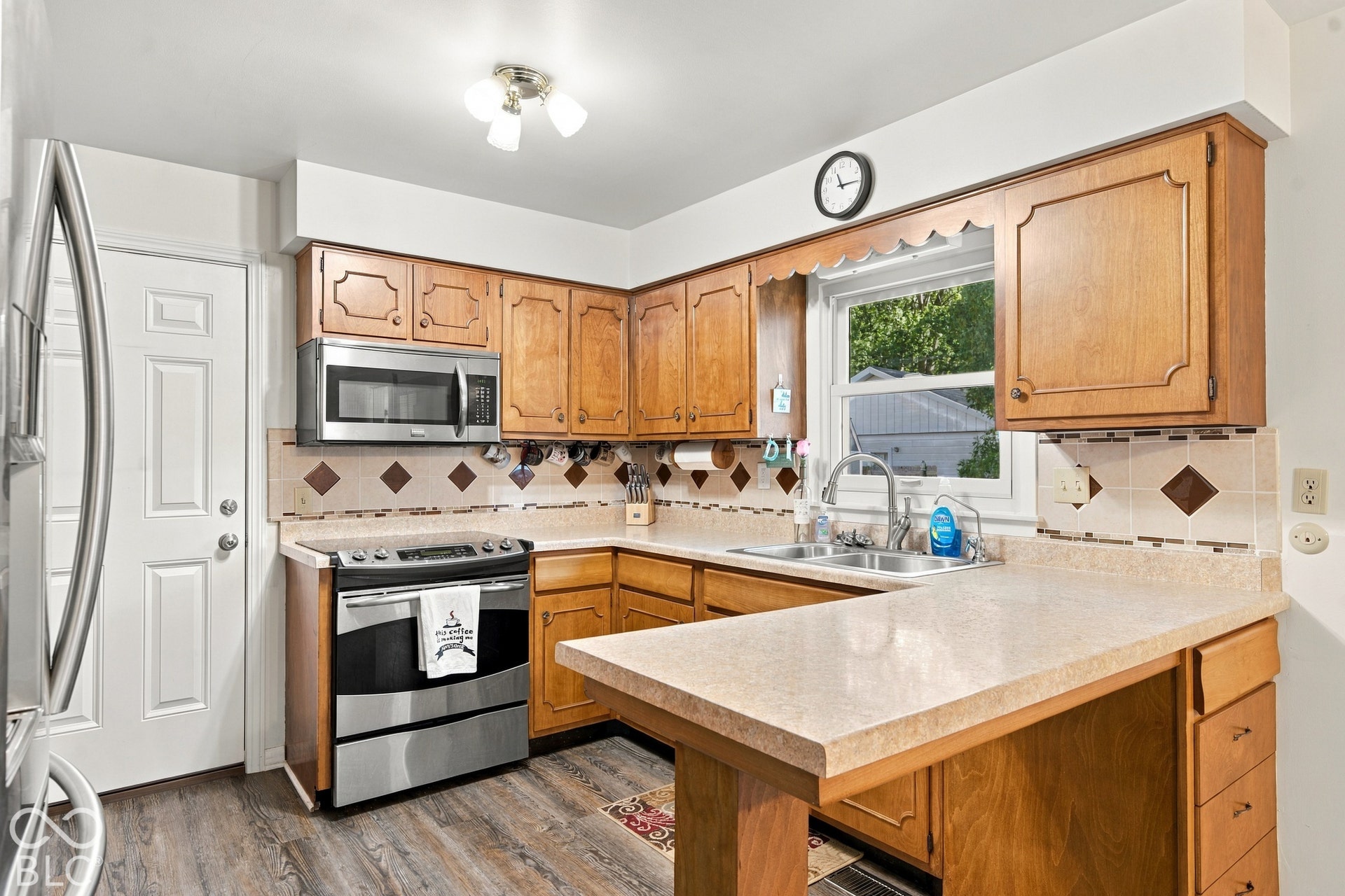 Wood-finish flooring, stainless steel appliances, wood cabinetry, and a double basin sink