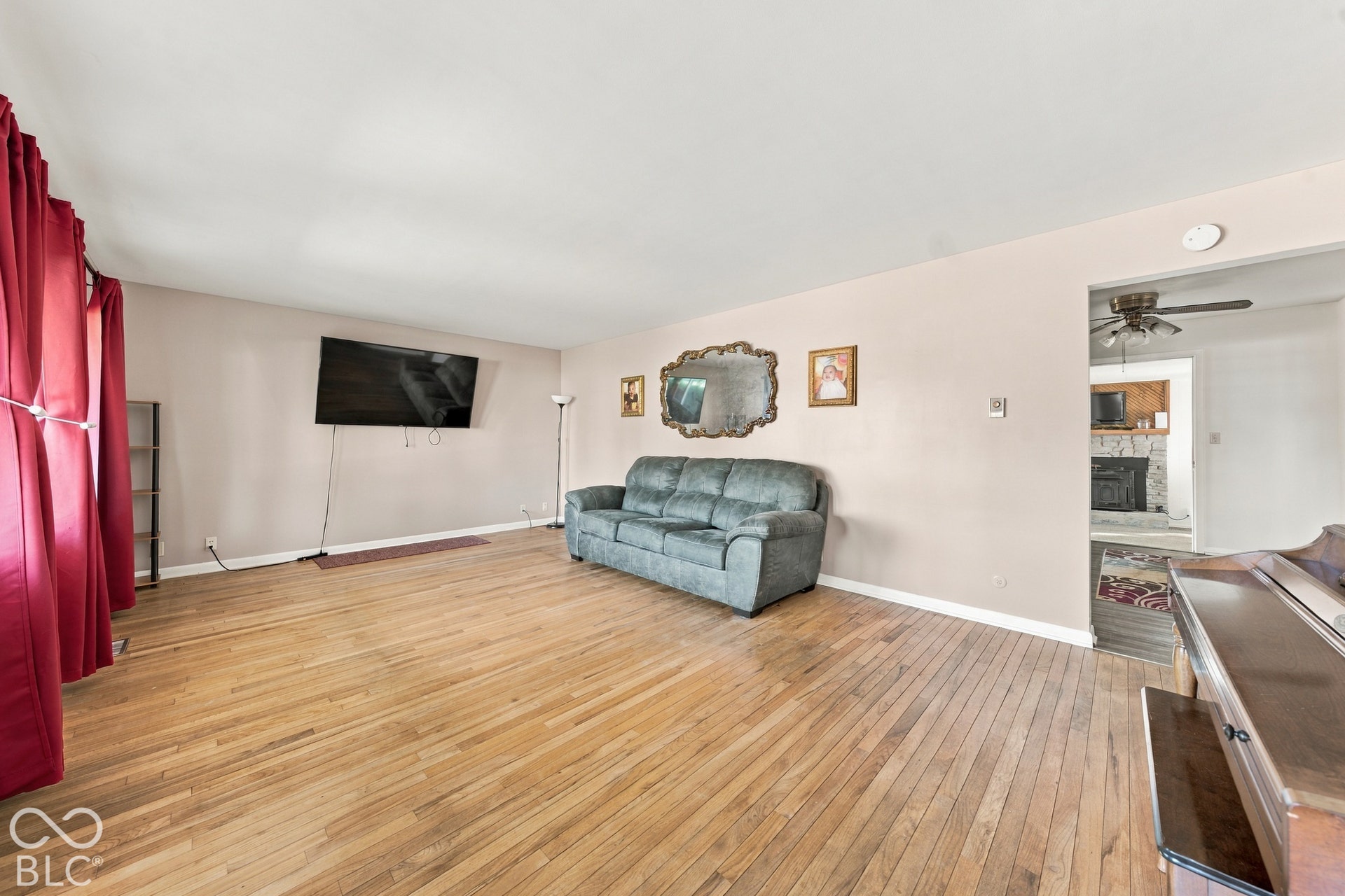Hardwood flooring throughout, neutral wall paint, and an open doorway to an additional room