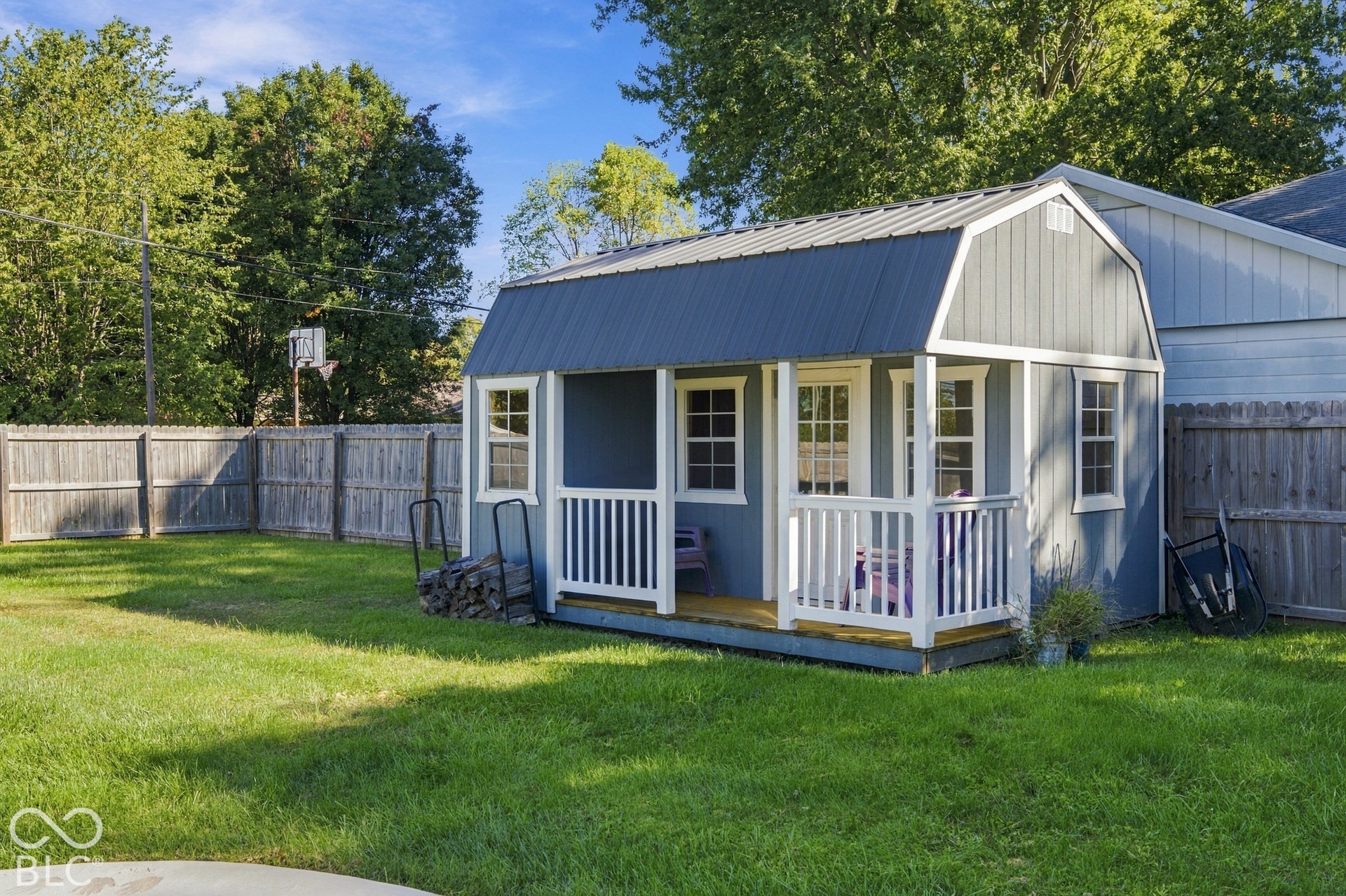 Spacious backyard with a separate storage shed featuring a porch, multiple windows, and a metal roof