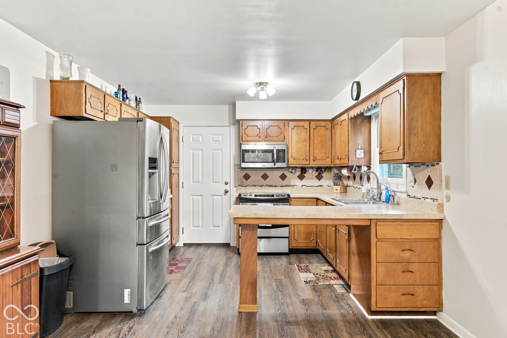 Kitchen featuring wood-finish flooring, wood cabinetry, a stainless steel refrigerator, microwave, and range
