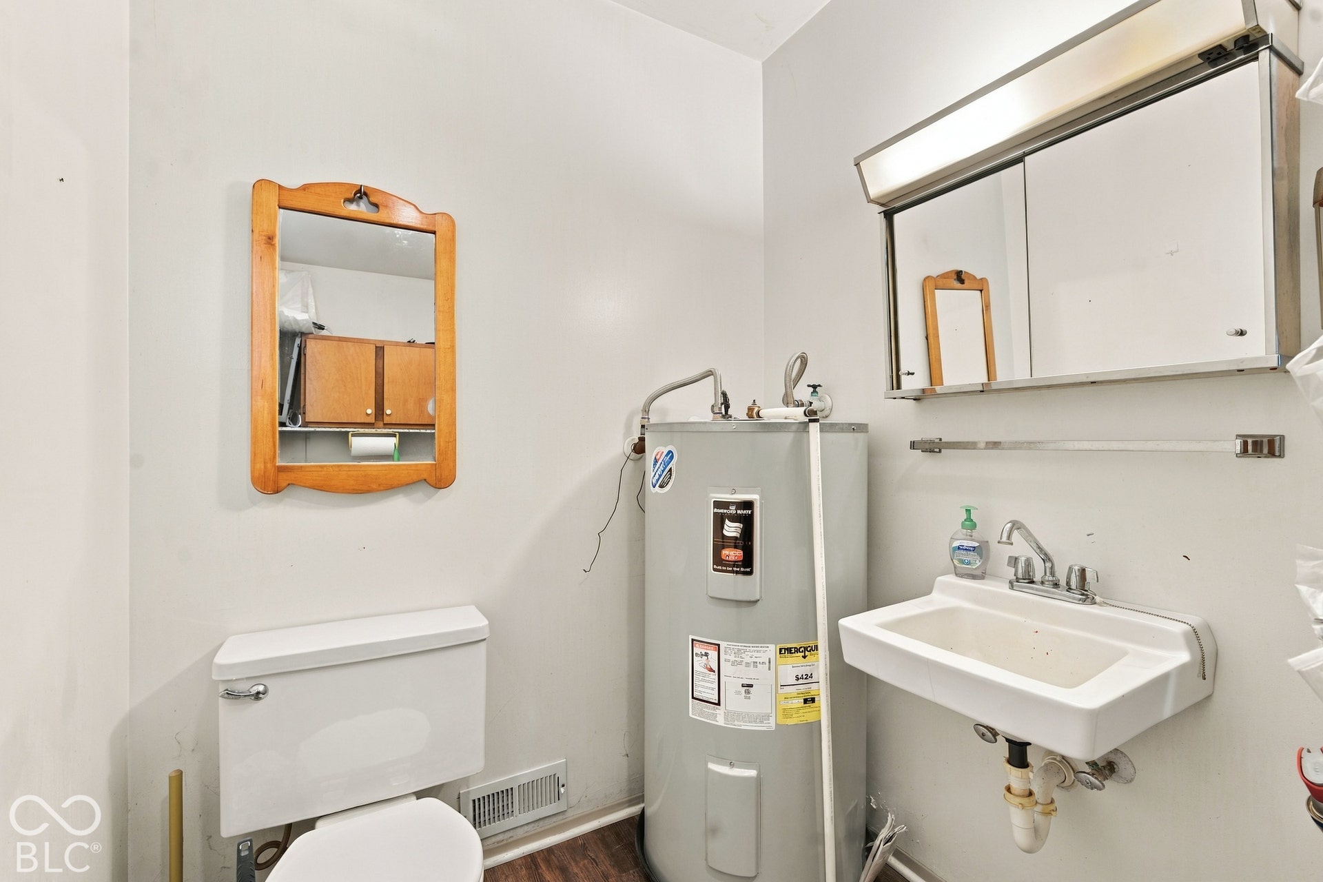 White wall-mounted sink with chrome faucet, medicine cabinet with integrated lighting, and a white toilet