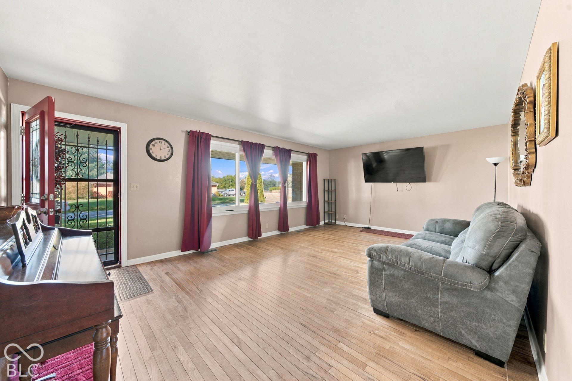 Hardwood flooring, multiple windows providing natural illumination, solid entry door with decorative security screen, and neutral wall tones