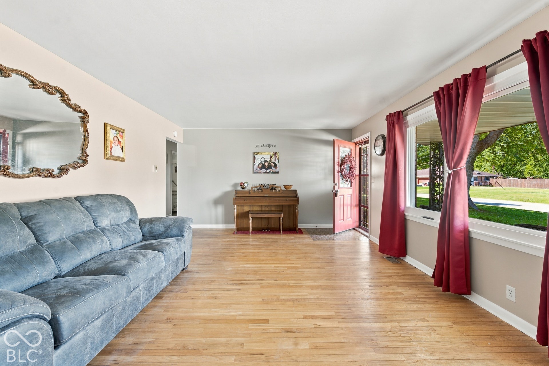 Wood-finish flooring throughout, light-toned wall paint, white ceiling, and a prominent front entry door