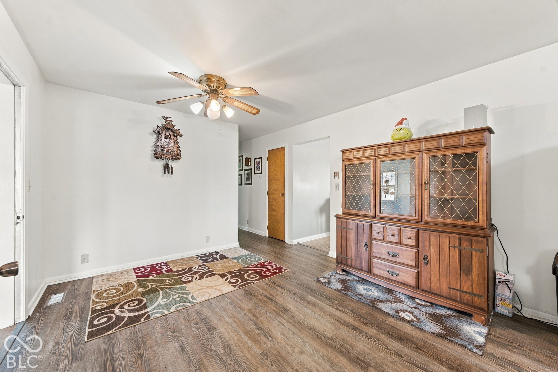 Wood-finish flooring throughout, bright white walls, and a ceiling fan with integrated lighting