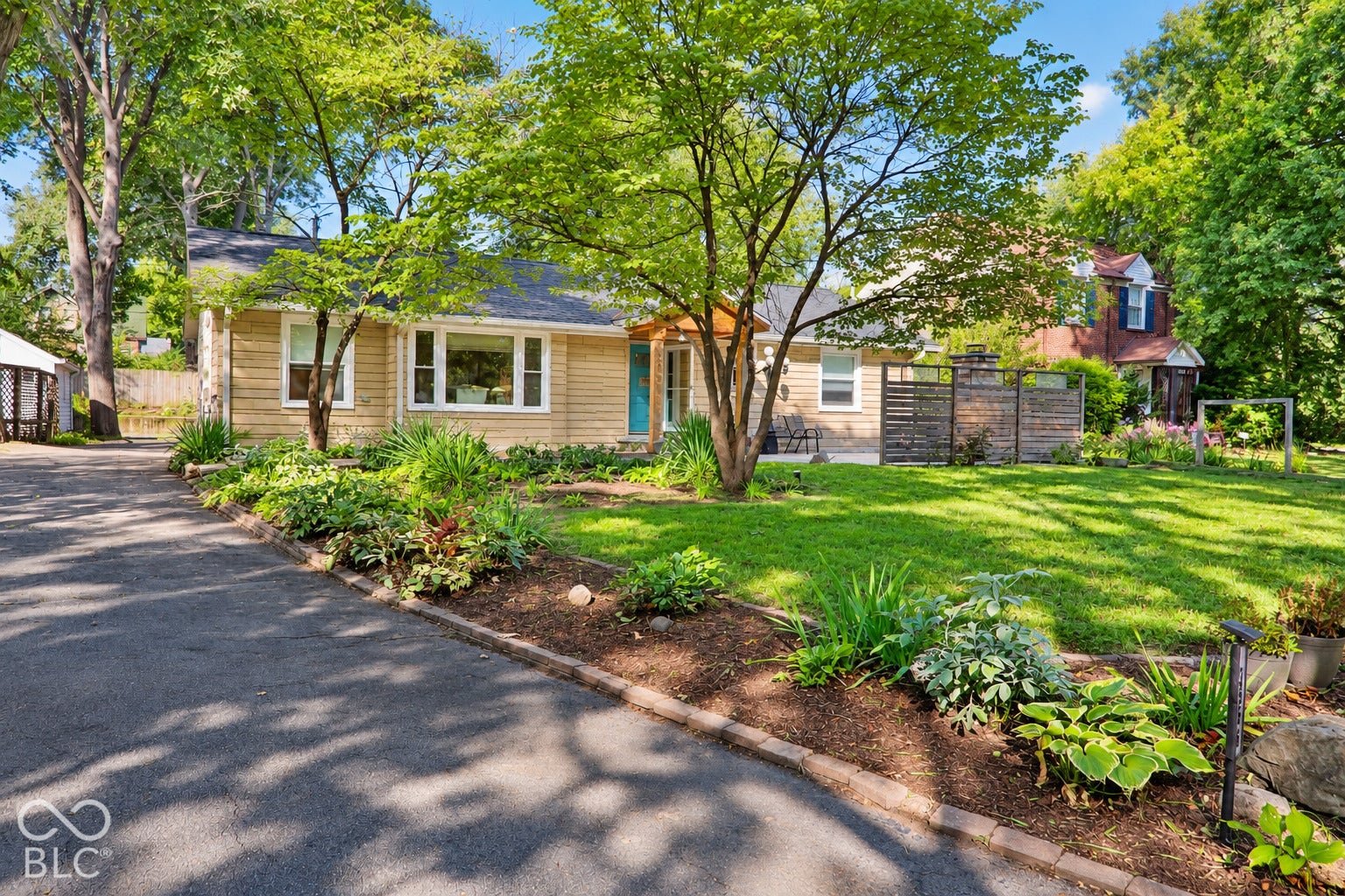 3566 Watson Road, Indianapolis, IN 46205 Siding exterior with multiple windows, mature trees, a manicured lawn, and lush landscaping