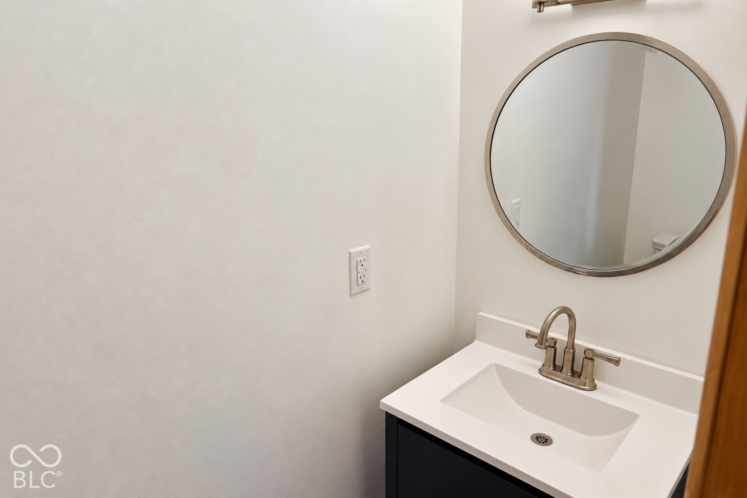 3566 Watson Road, Indianapolis, IN 46205 Vanity with a white countertop and integrated sink, brushed nickel faucet, and circular framed mirror