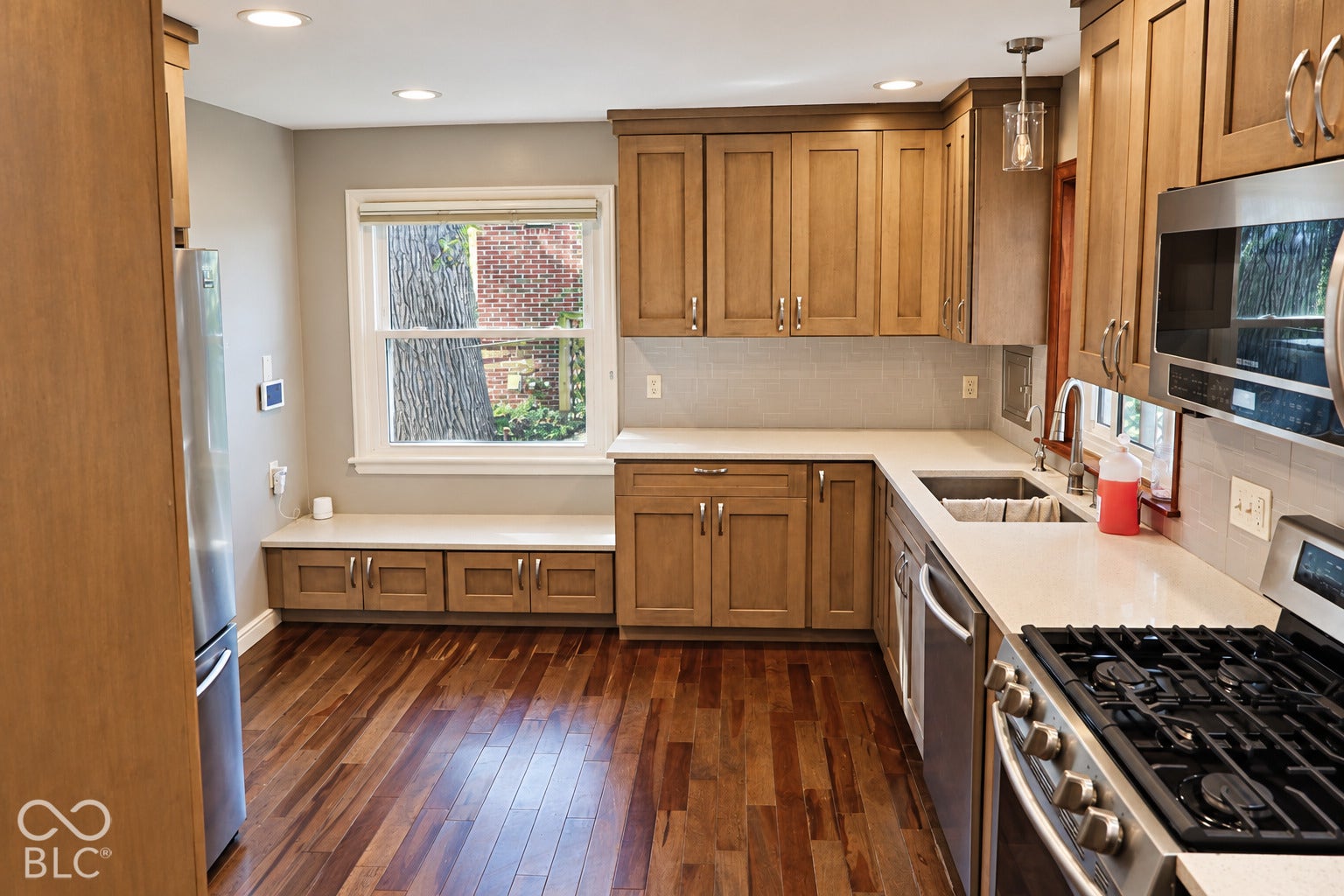 3566 Watson Road, Indianapolis, IN 46205 Wood-finish flooring, recessed lighting, built-in bench seating with cabinetry, light-toned countertops, and a tile backsplash