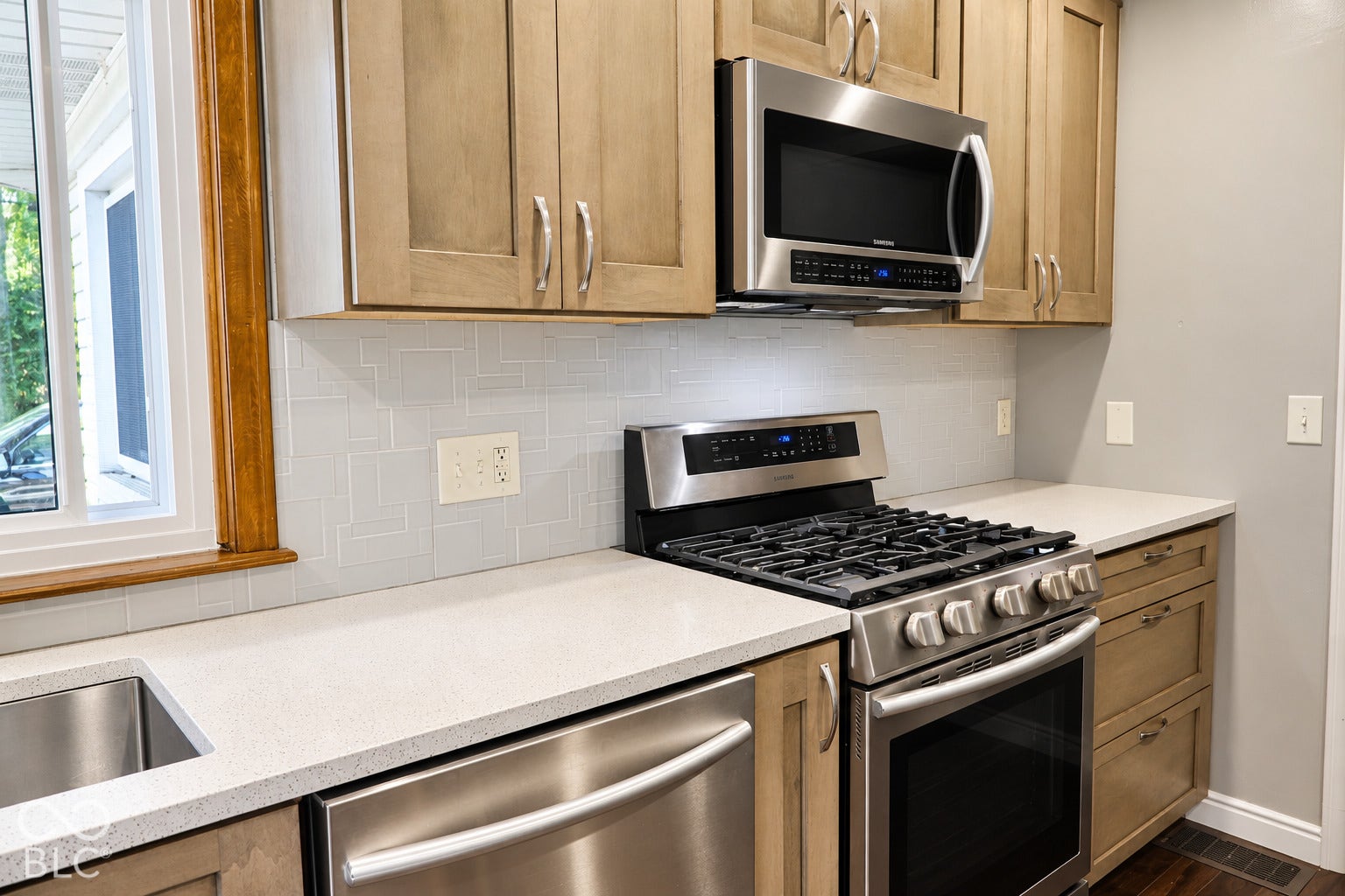 3566 Watson Road, Indianapolis, IN 46205 Stainless steel appliances, light-toned cabinetry, solid surface countertops, light-toned tile backsplash, and an undermount sink