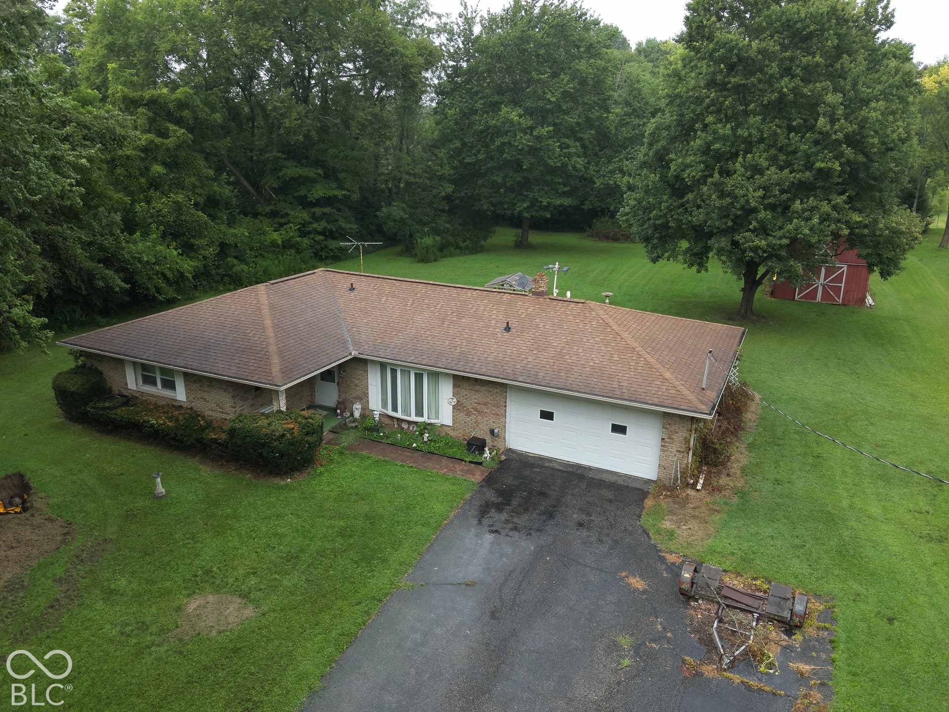Brick-clad residence with a pitched shingle roof, attached two-car garage, paved driveway, and expansive lawn