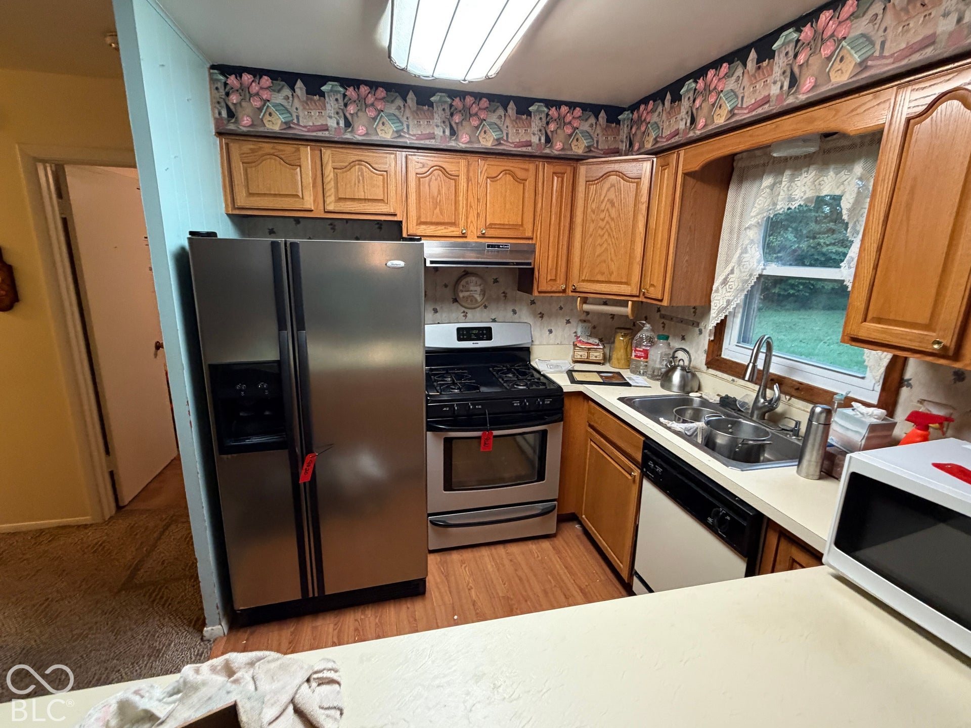 Kitchen featuring wood-finish cabinetry, stainless steel side-by-side refrigerator, stainless steel gas range, and a double-basin stainless steel sink