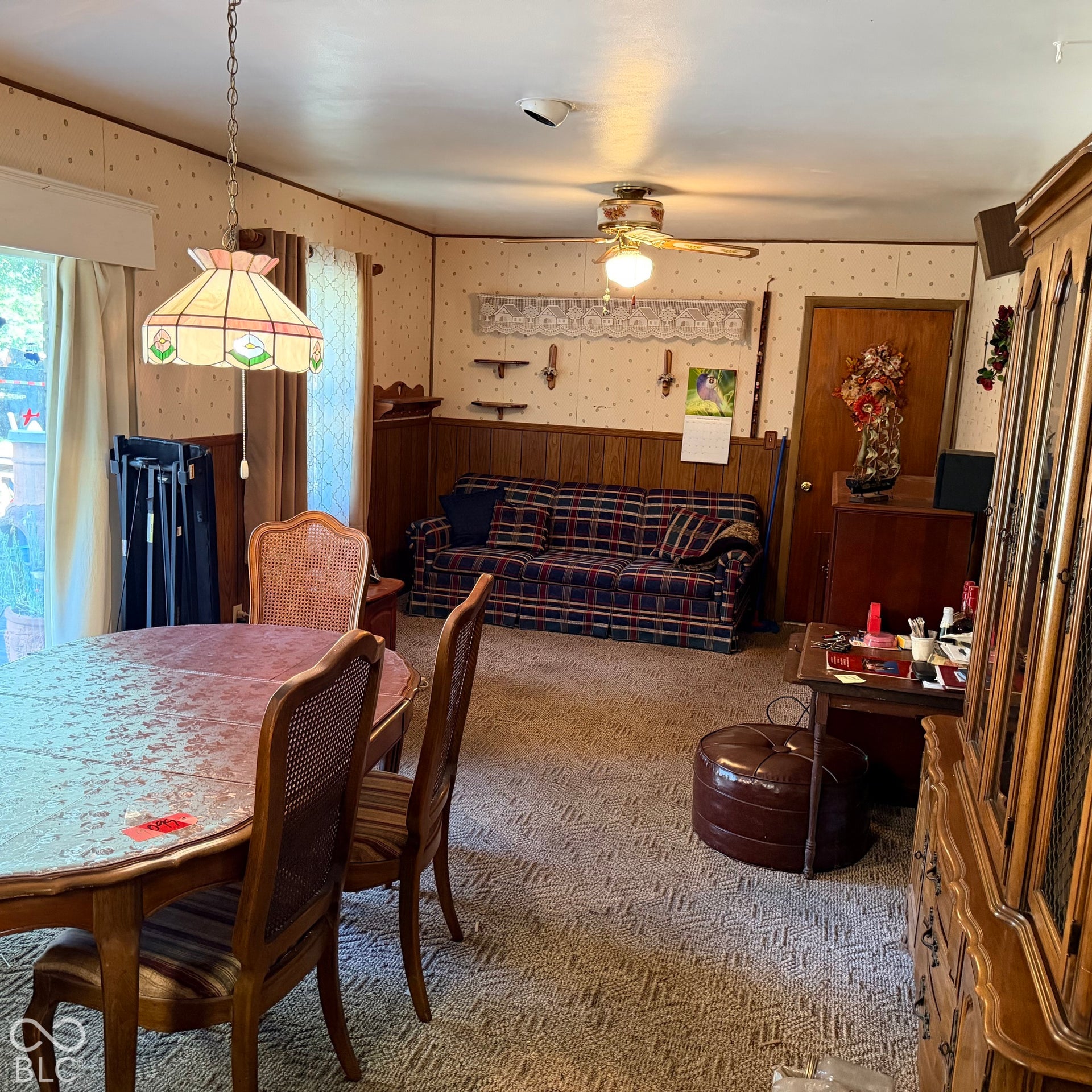 Patterned carpeting, wood wainscoting, and a ceiling fan with integrated lighting