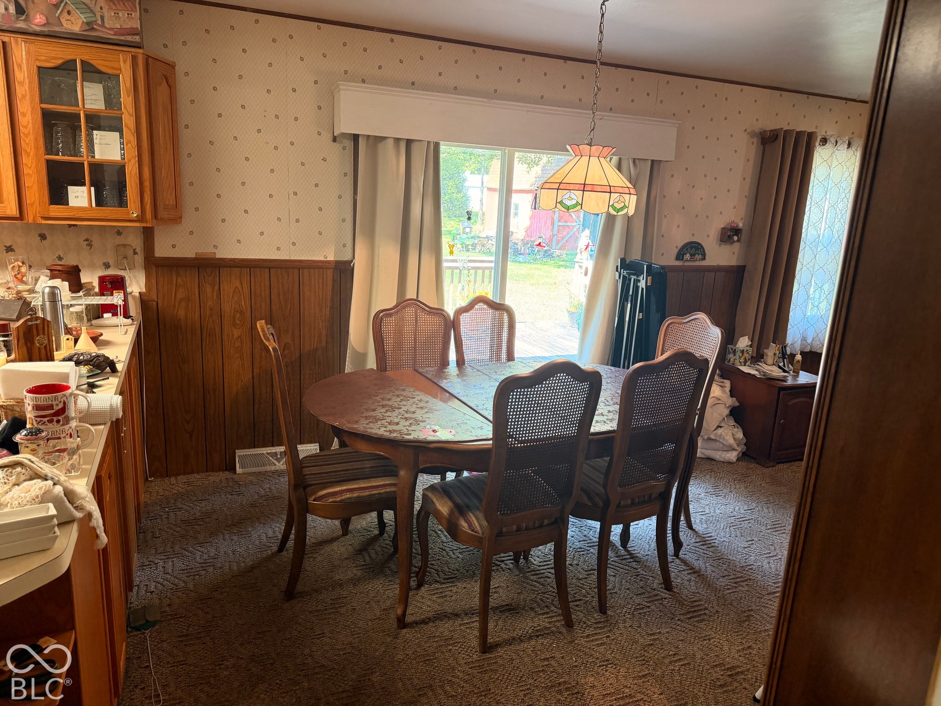 Dining area with wood paneling, patterned wallpaper, and carpeted flooring