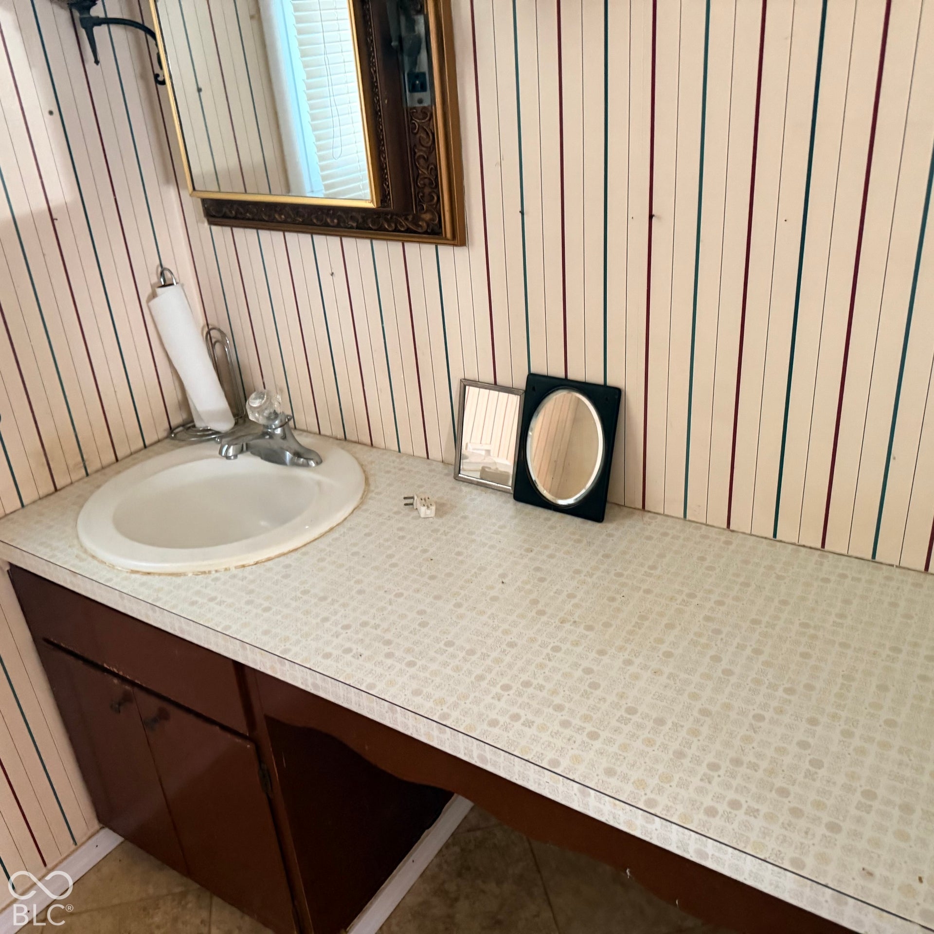 Built-in vanity with a drop-in sink, chrome-finish faucet, and patterned countertop