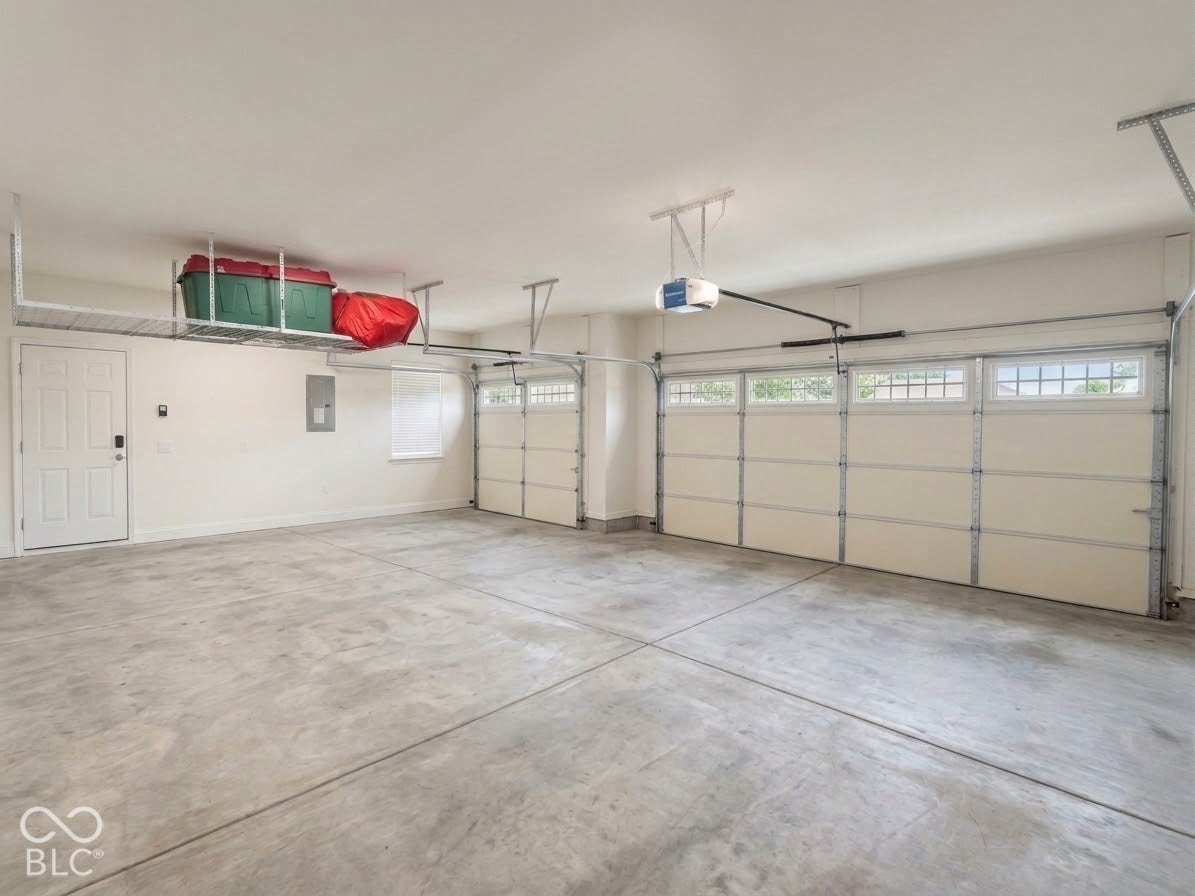 Attached two-car garage with overhead storage, concrete flooring, and automatic garage door openers