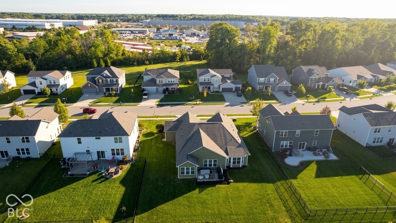 Residential streetscape featuring multiple two-story homes with attached garages, manicured lawns, and paved driveways