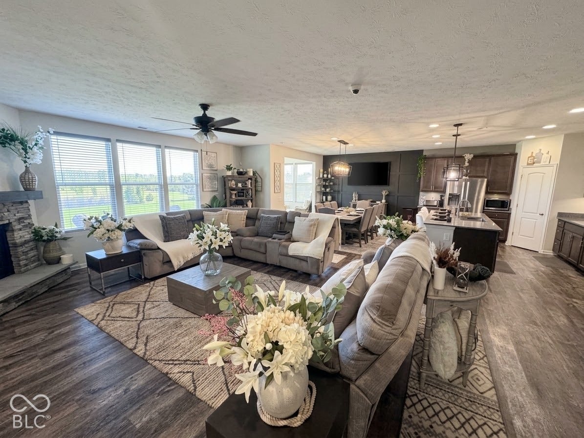 Spacious interior featuring wood-finish flooring, a stone-clad fireplace, and multiple windows