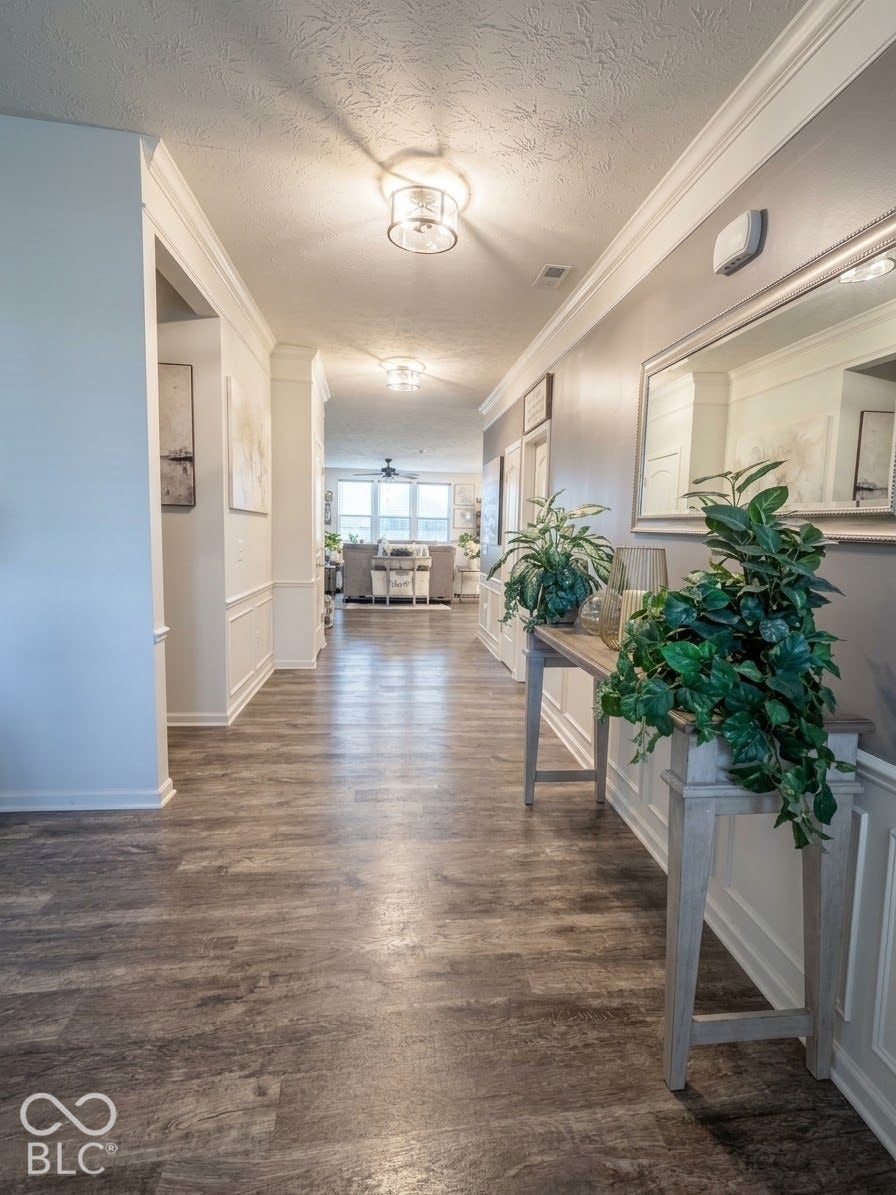 Wood-finish flooring extending through the hallway, complemented by wainscoting and crown molding