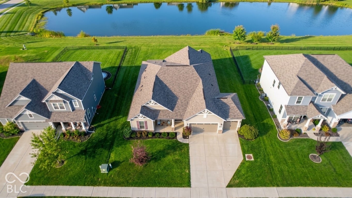 Waterfront property featuring an expansive green lawn, asphalt shingle roofing, and concrete driveways