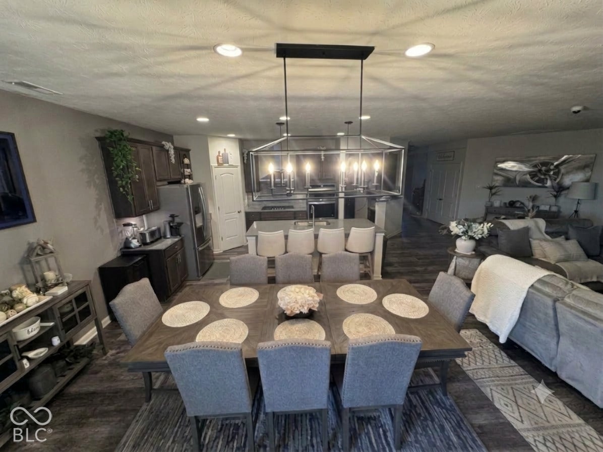 Recessed lighting, wood-finish flooring, dark wood-finish cabinetry, and a central island with bar seating
