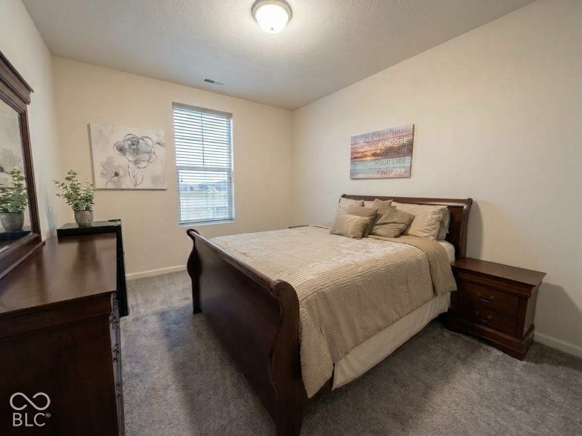 Carpeted room with a single window featuring blinds, an overhead light fixture, and neutral painted walls