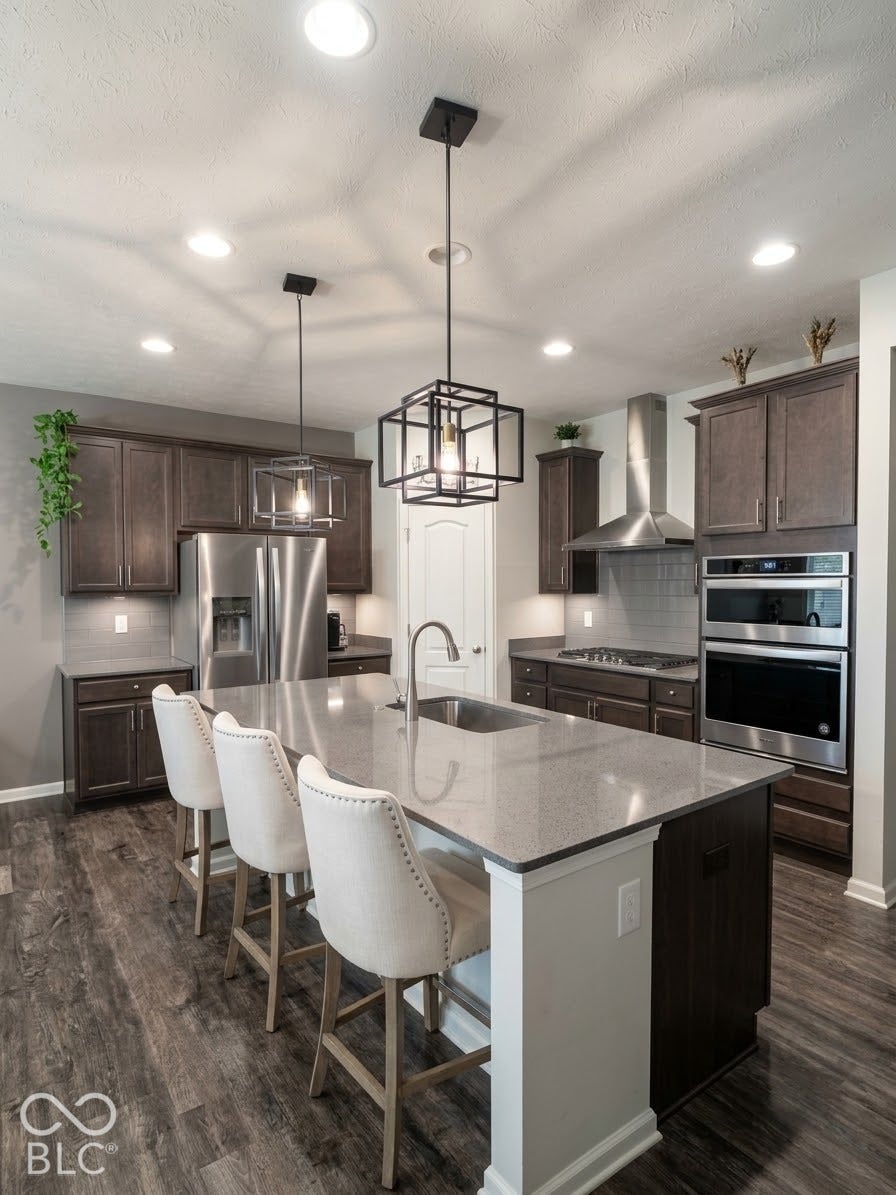 Kitchen featuring wood-finish flooring, dark wood cabinetry, a center island with countertop seating, stainless steel appliances, and recessed lighting
