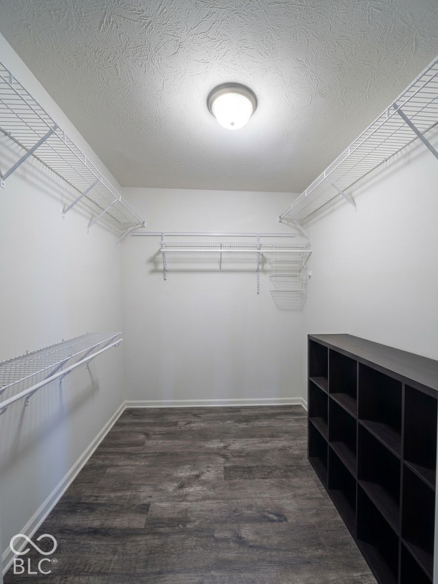 Recessed ceiling light fixture, white wire shelving system, built-in black storage cubbies, and wood-finish flooring
