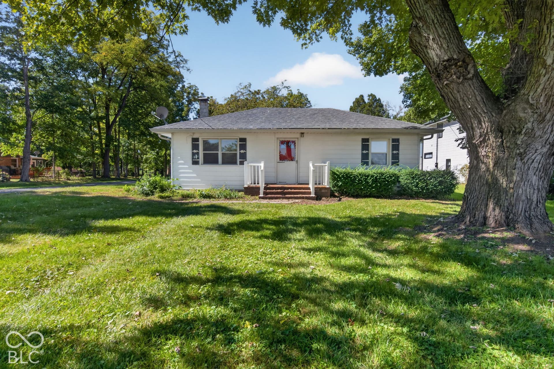 White siding exterior with dark shutters, front porch with white railing, and exterior chimney