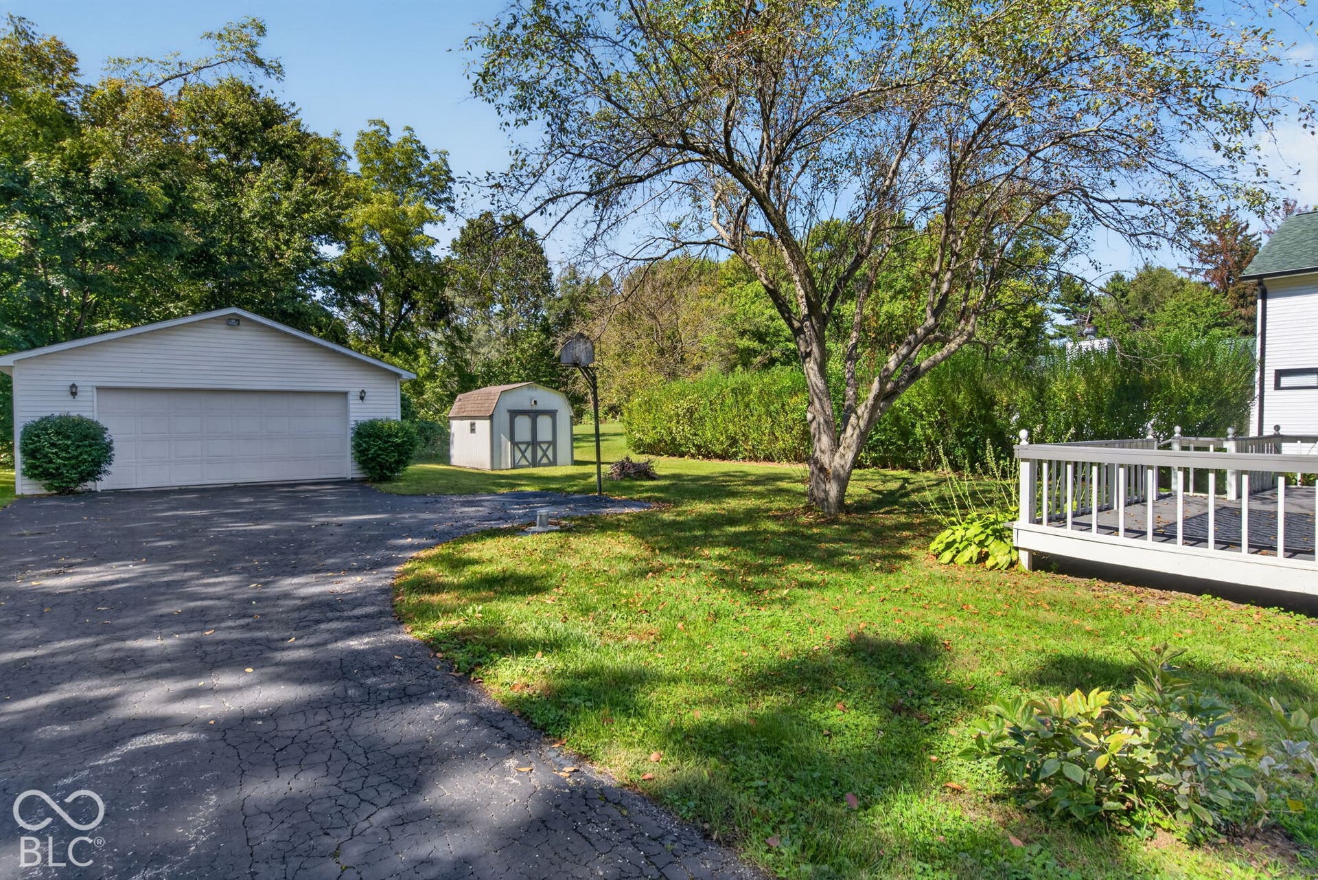 Expansive outdoor space featuring a detached two-car garage, storage shed, and a composite deck with railing