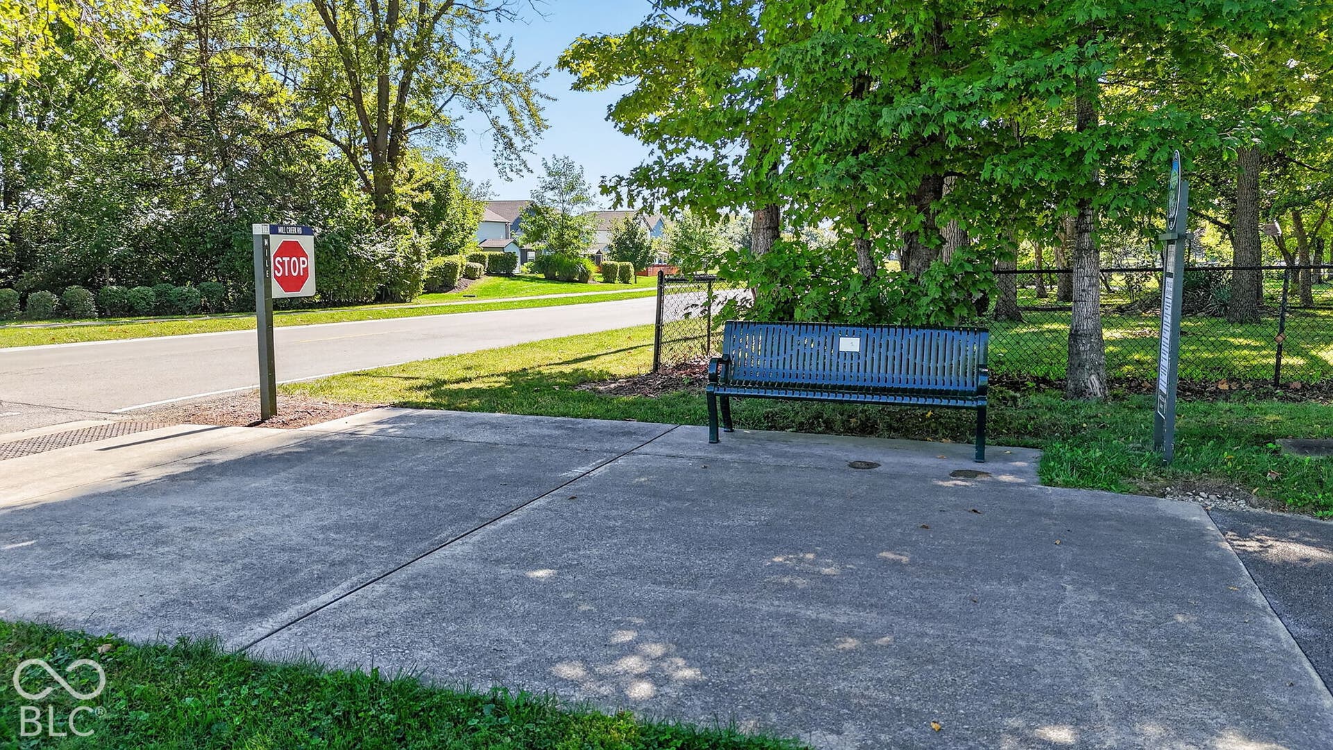 Concrete pad with a metal slatted bench and chain-link fencing