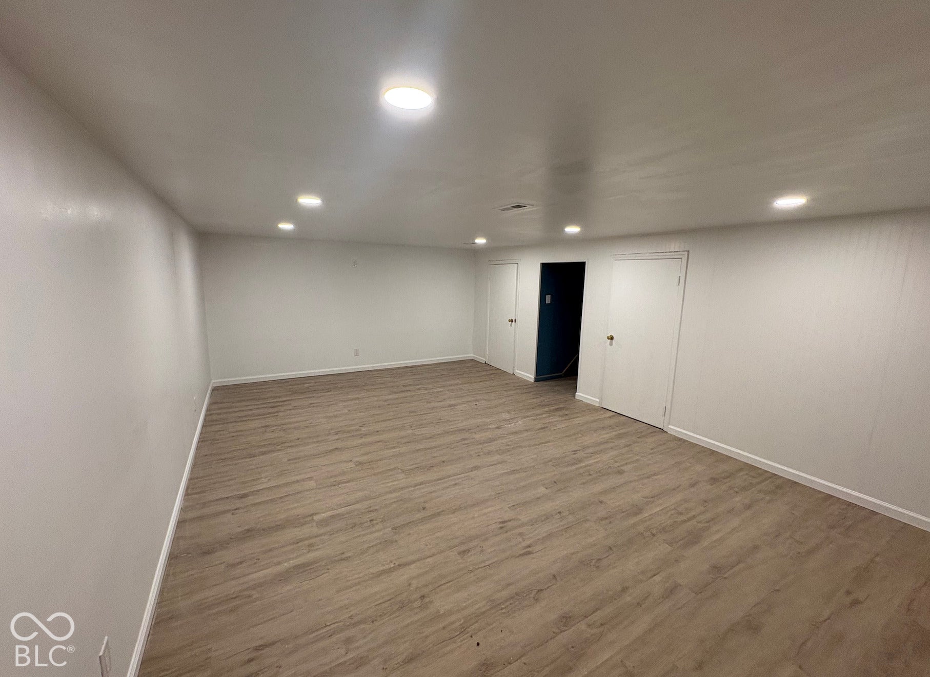 Spacious room featuring wood-finish flooring and recessed lighting