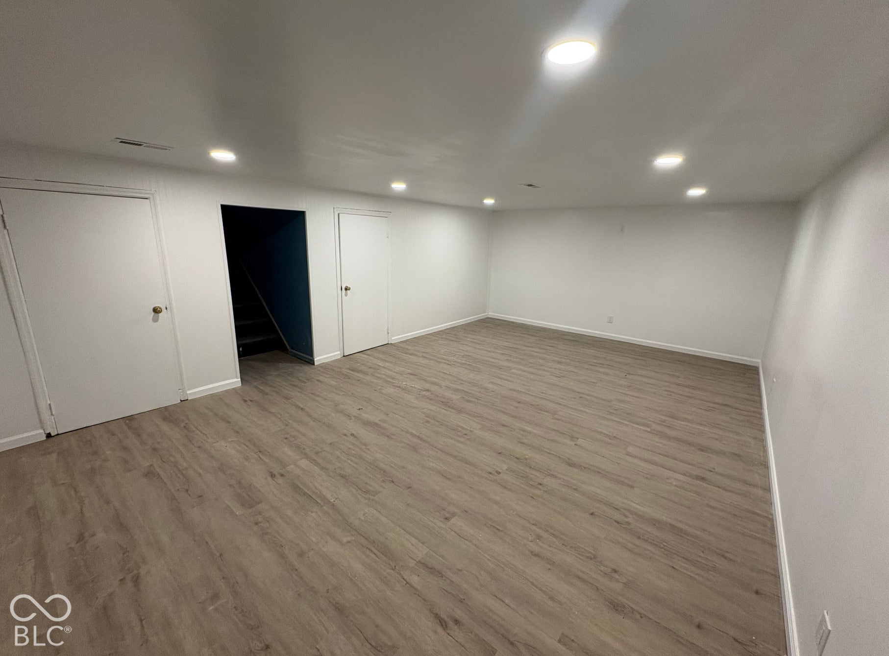 Recessed ceiling lighting, wood-finish flooring, white walls, and white trim