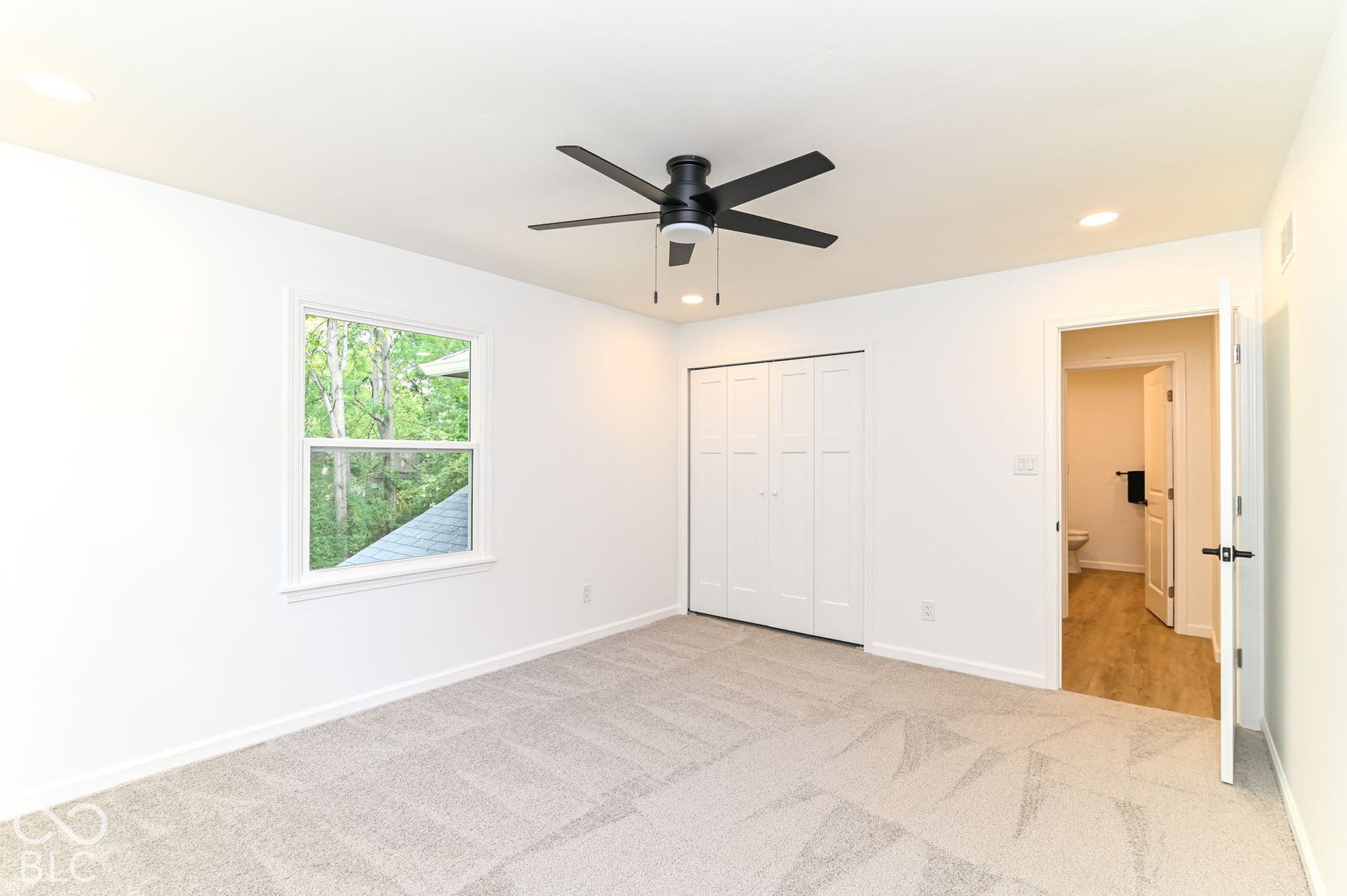 Recessed lighting, ceiling fan, bi-fold closet doors, window with white trim, and light-toned patterned carpeting