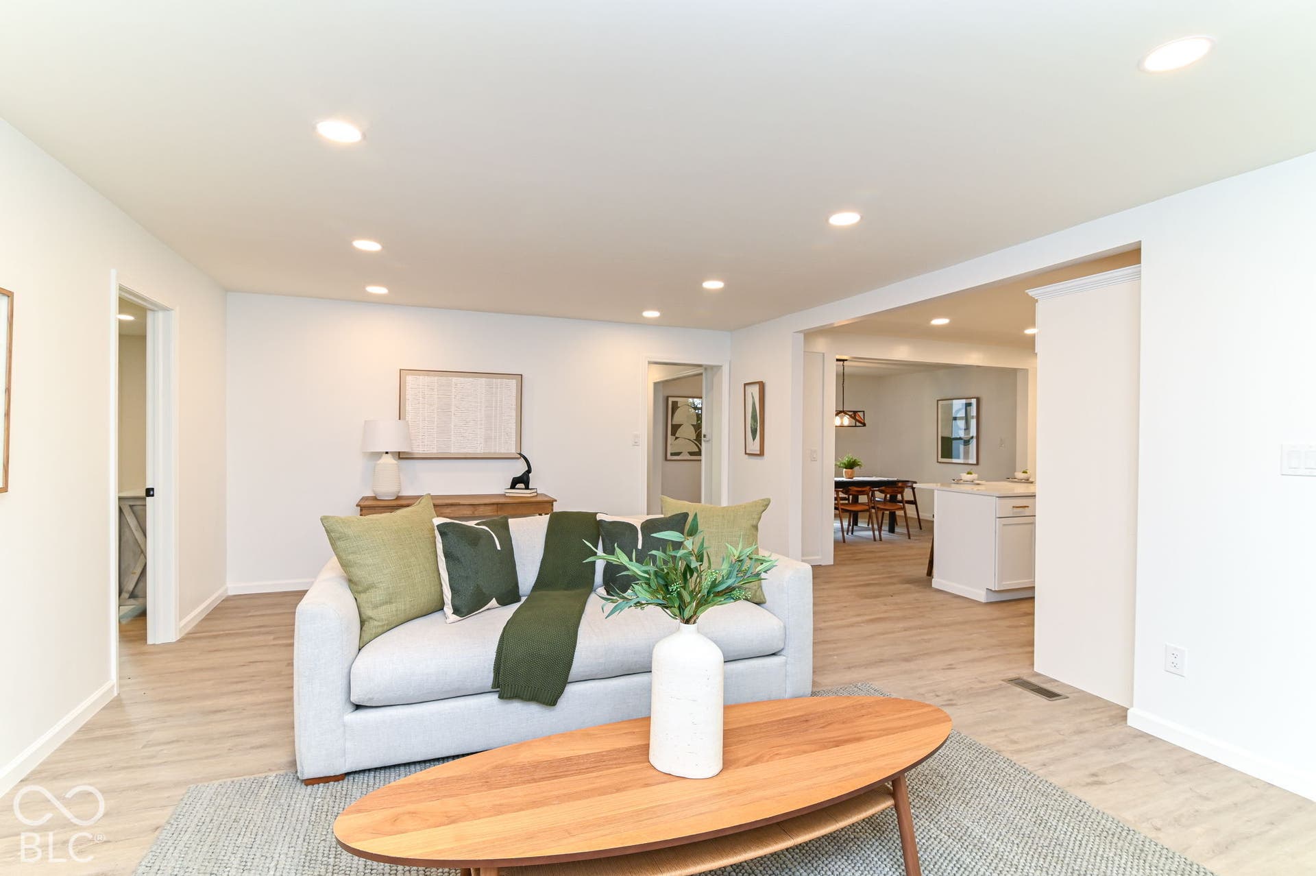 Recessed ceiling lighting, light wood-finish flooring, white painted walls, and open room transitions