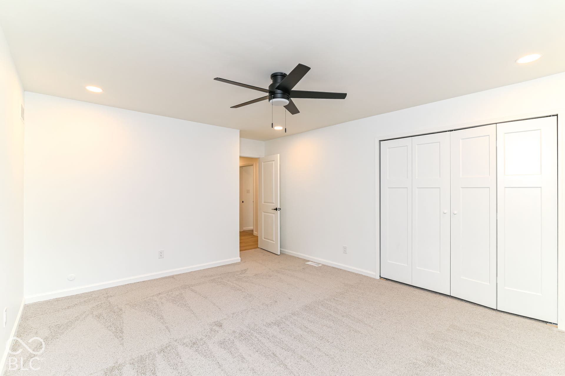Recessed lighting, ceiling fan with matte black finish, light-toned carpeting, white bi-fold closet doors, and white walls