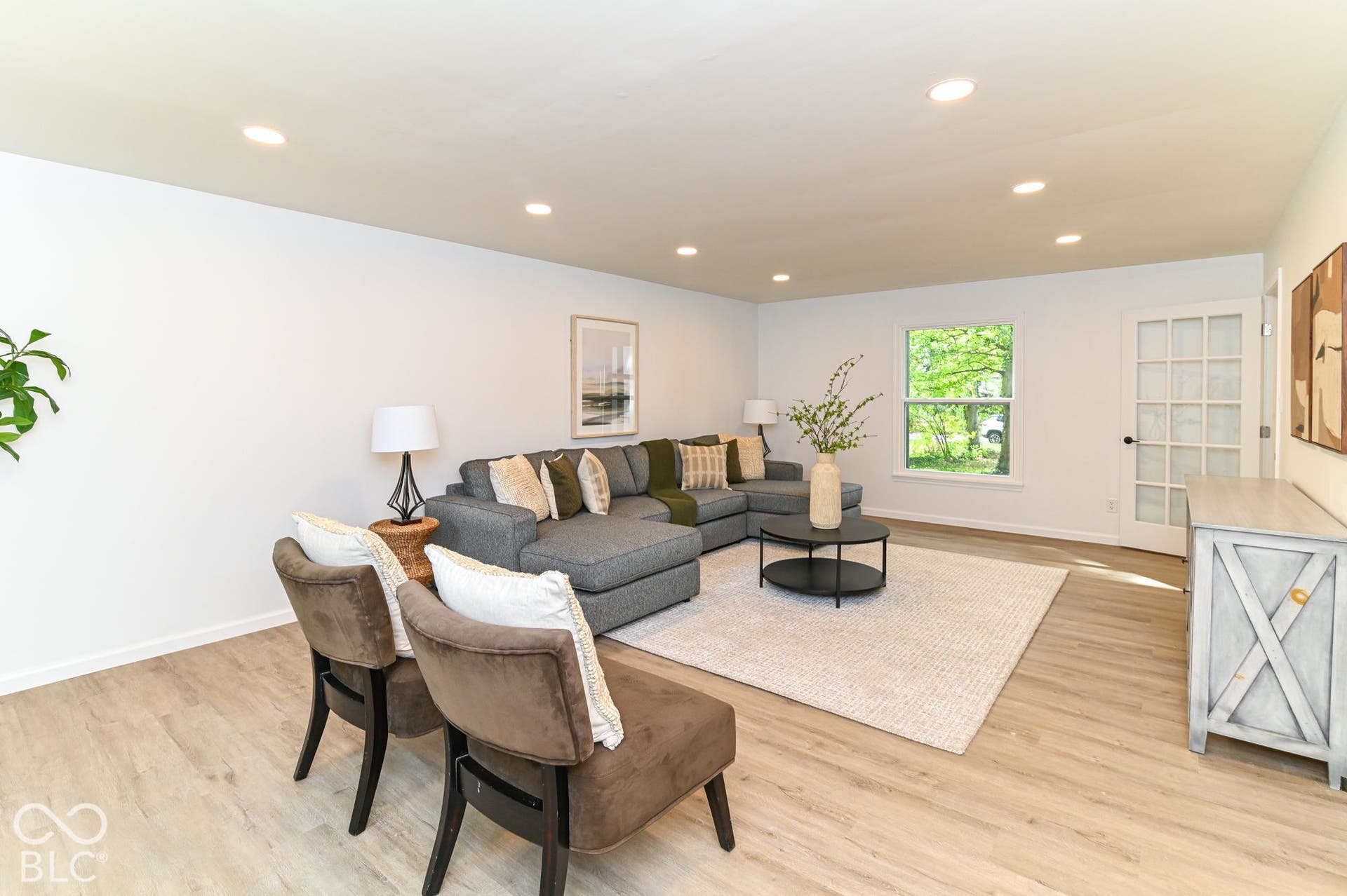 Recessed lighting, light wood-finish flooring, white walls, and a white French door