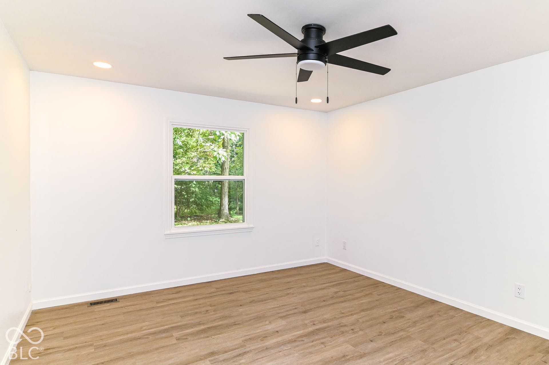 Recessed lighting, wood-finish flooring, white walls, and a black ceiling fan with integrated lighting