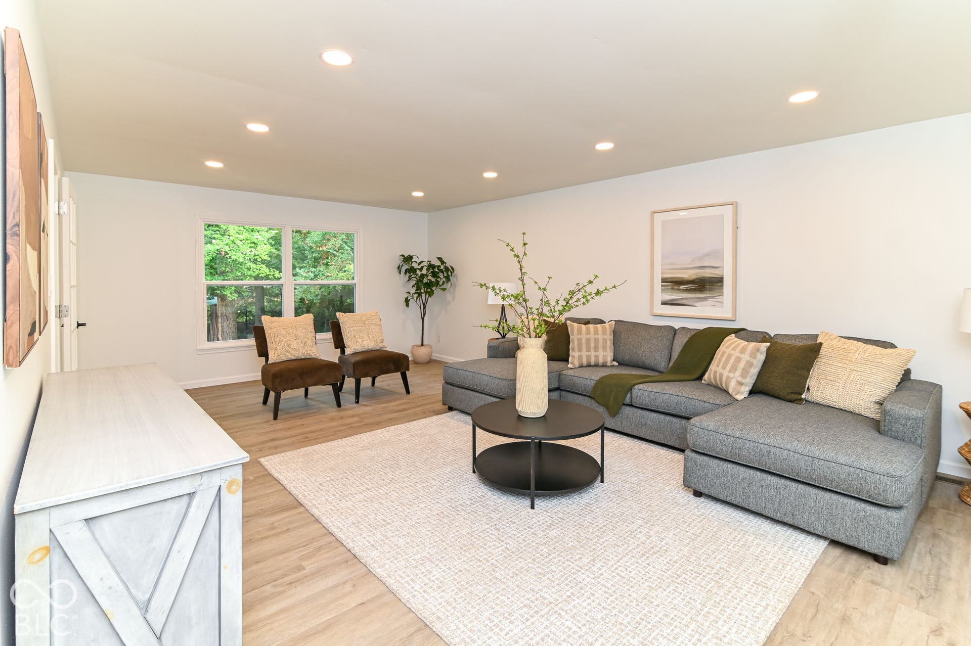 Recessed lighting illuminates the open living area featuring wood-finish flooring and large windows