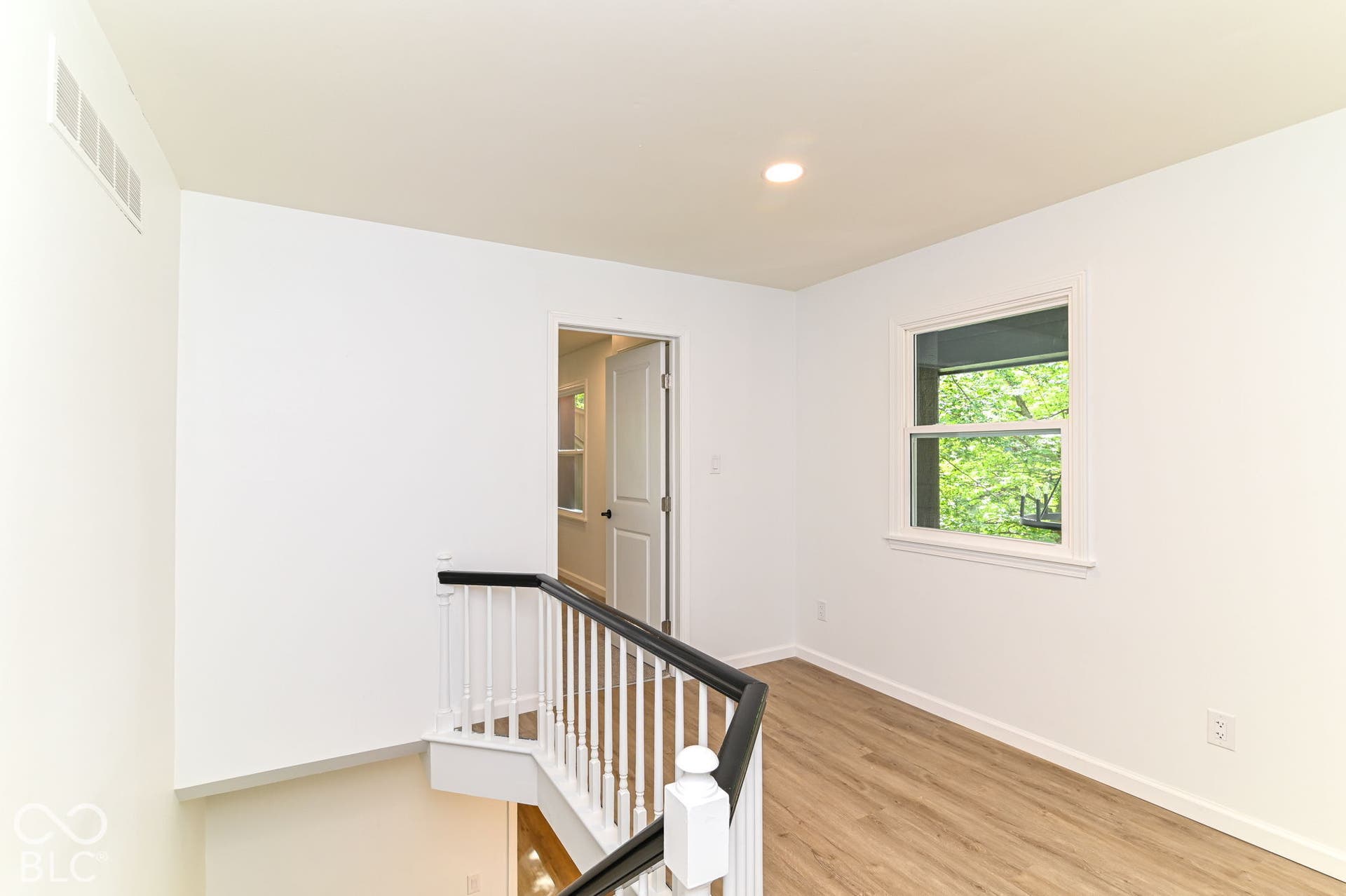 Wood-finish flooring, white walls, recessed lighting, and a window with white trim