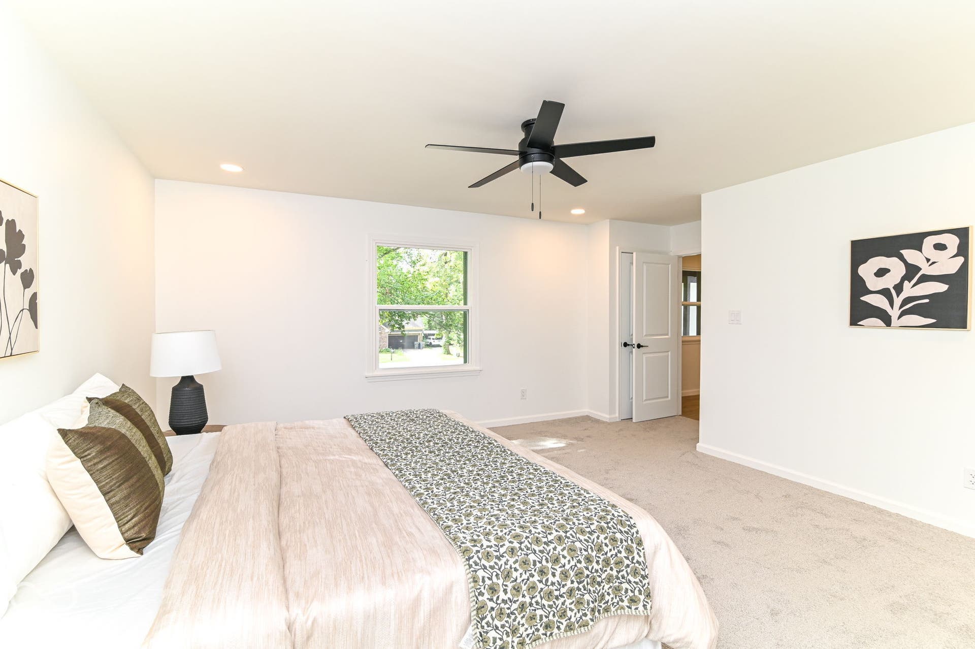 Recessed lighting, light-toned carpeting, white interior walls, white paneled door with black hardware, and a ceiling fan with a matte black finish
