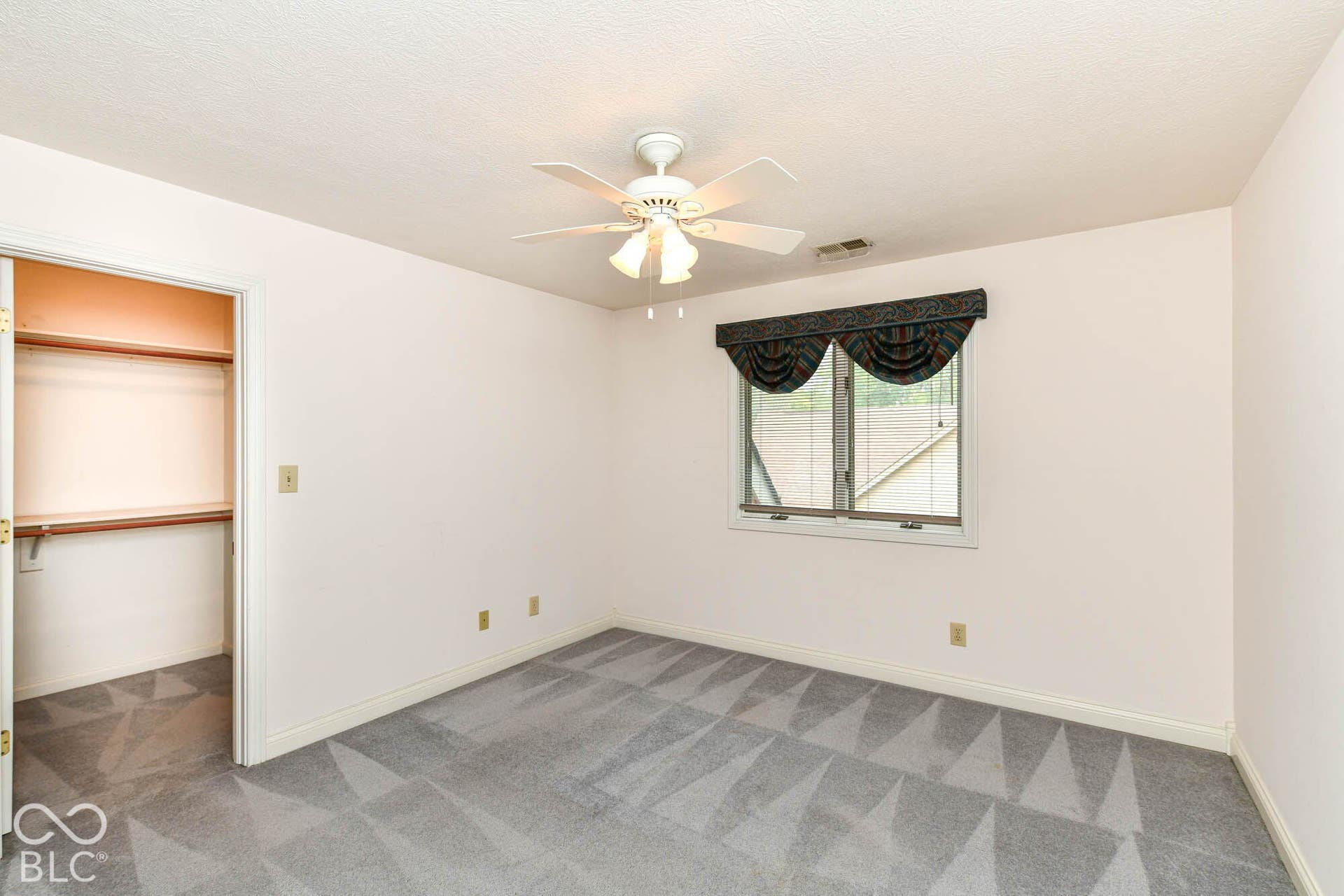 6431 Shamel Drive, Indianapolis, IN 46278 Upper Bedroom. Recessed closet with built-in shelving, patterned carpeting, ceiling fan, and window with valance