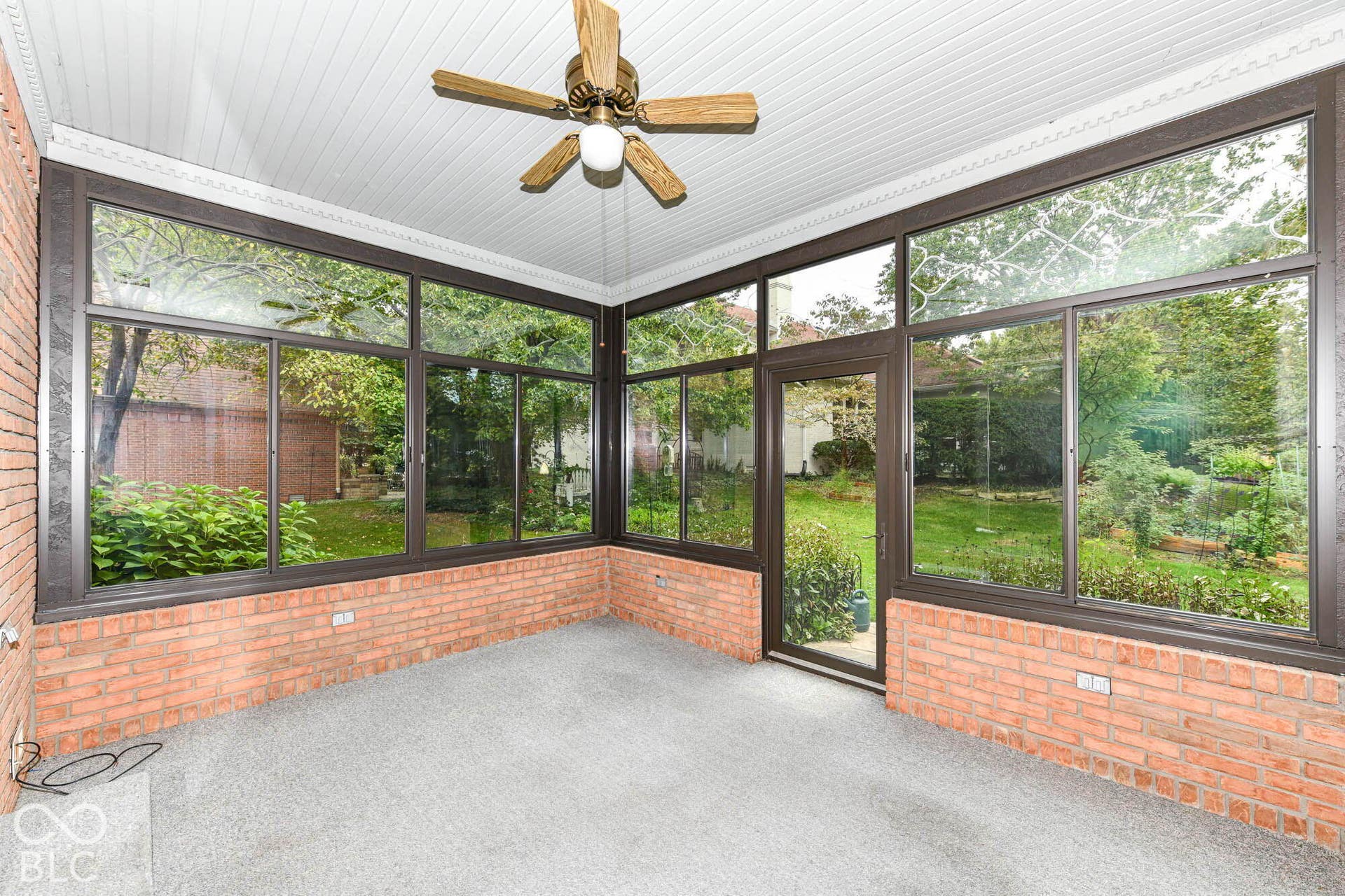 6431 Shamel Drive, Indianapolis, IN 46278 Four-Season Sun Room off Kitchen. Enclosed sunroom featuring extensive windows, brick knee walls, and a ceiling fan