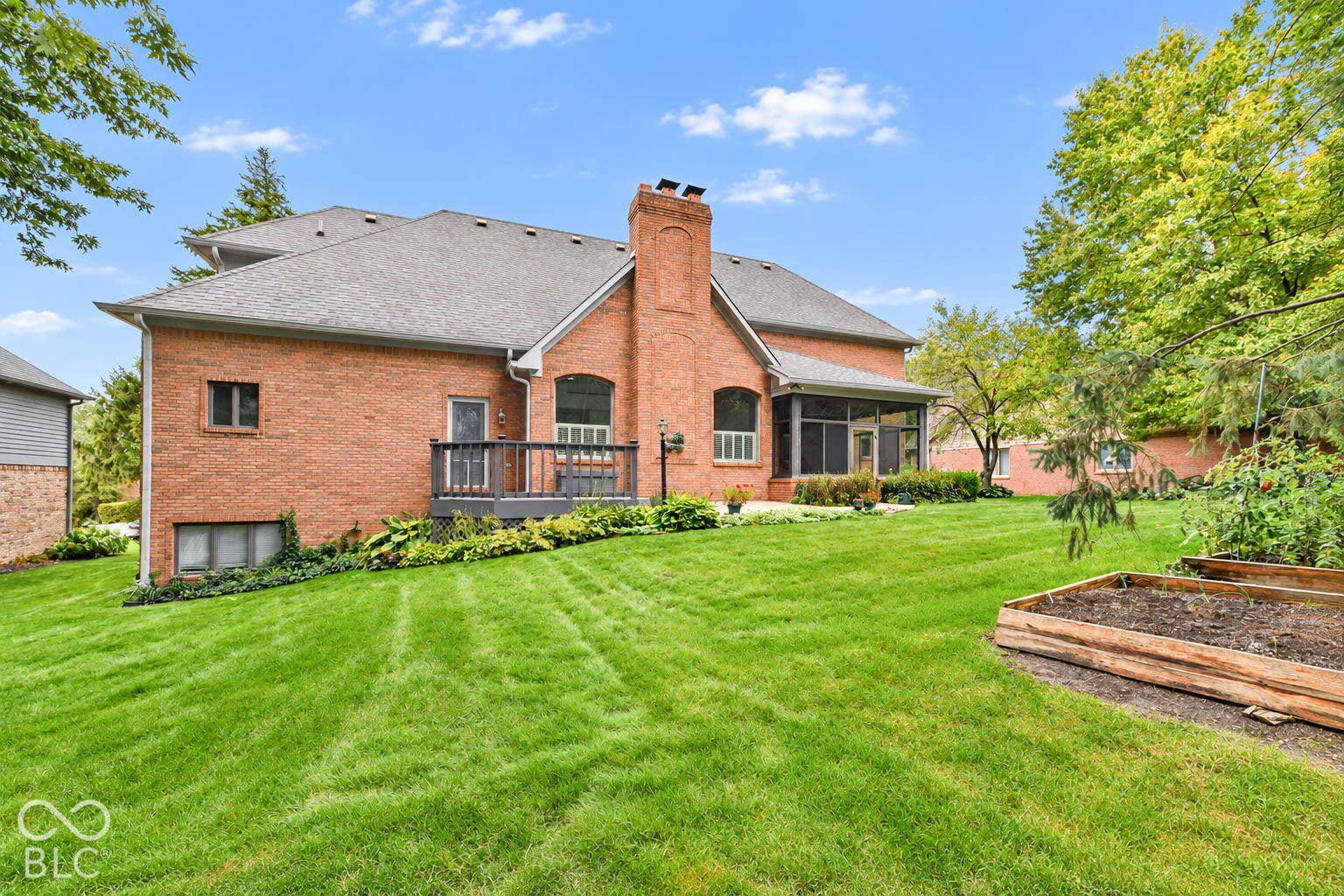 6431 Shamel Drive, Indianapolis, IN 46278 Brick exterior with a prominent chimney, gray shingle roof, and four-season room