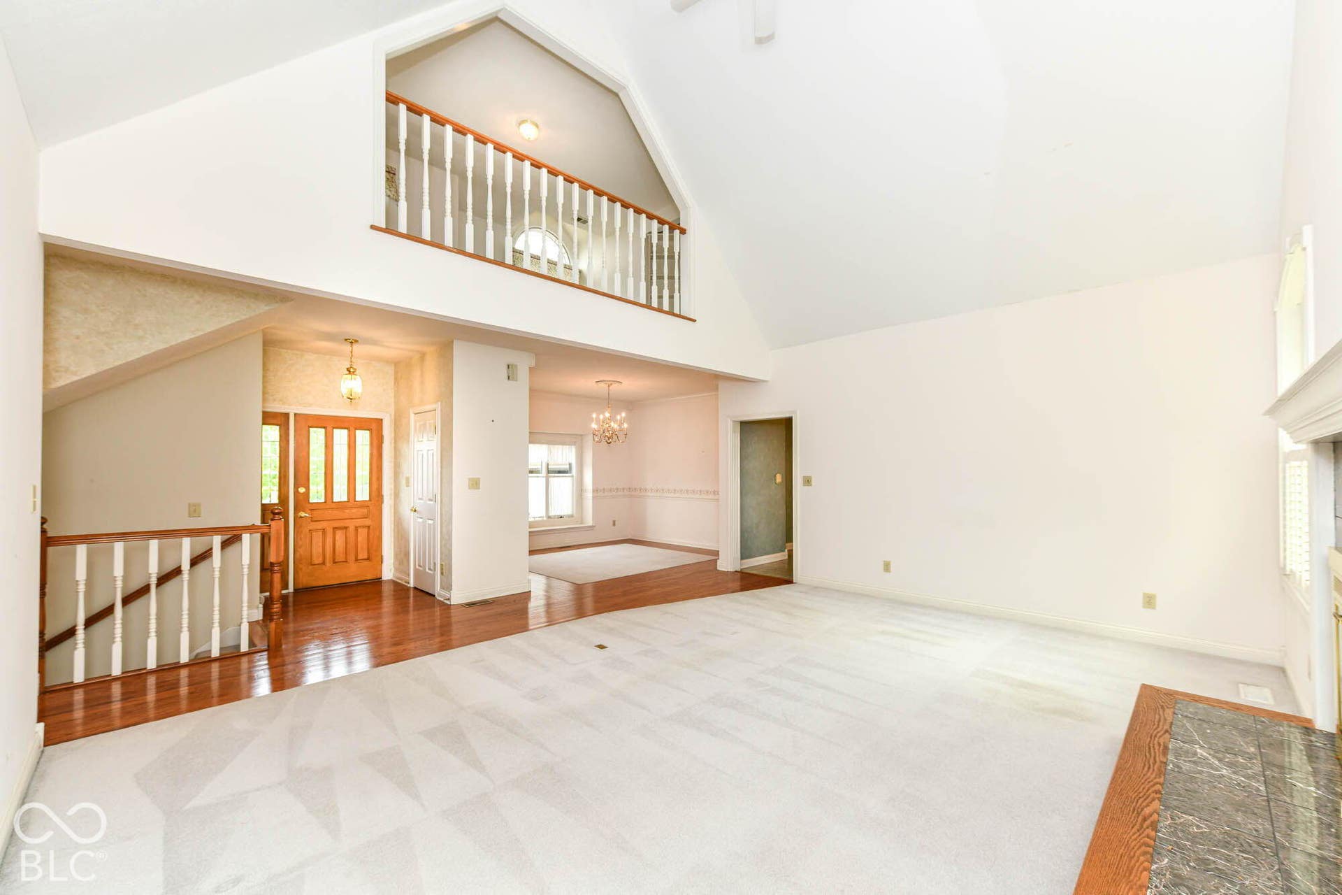 6431 Shamel Drive, Indianapolis, IN 46278 Great Room. Vaulted ceiling, wood-finish flooring, staircase with wood railing, interior balcony, and a fireplace with a stone surround