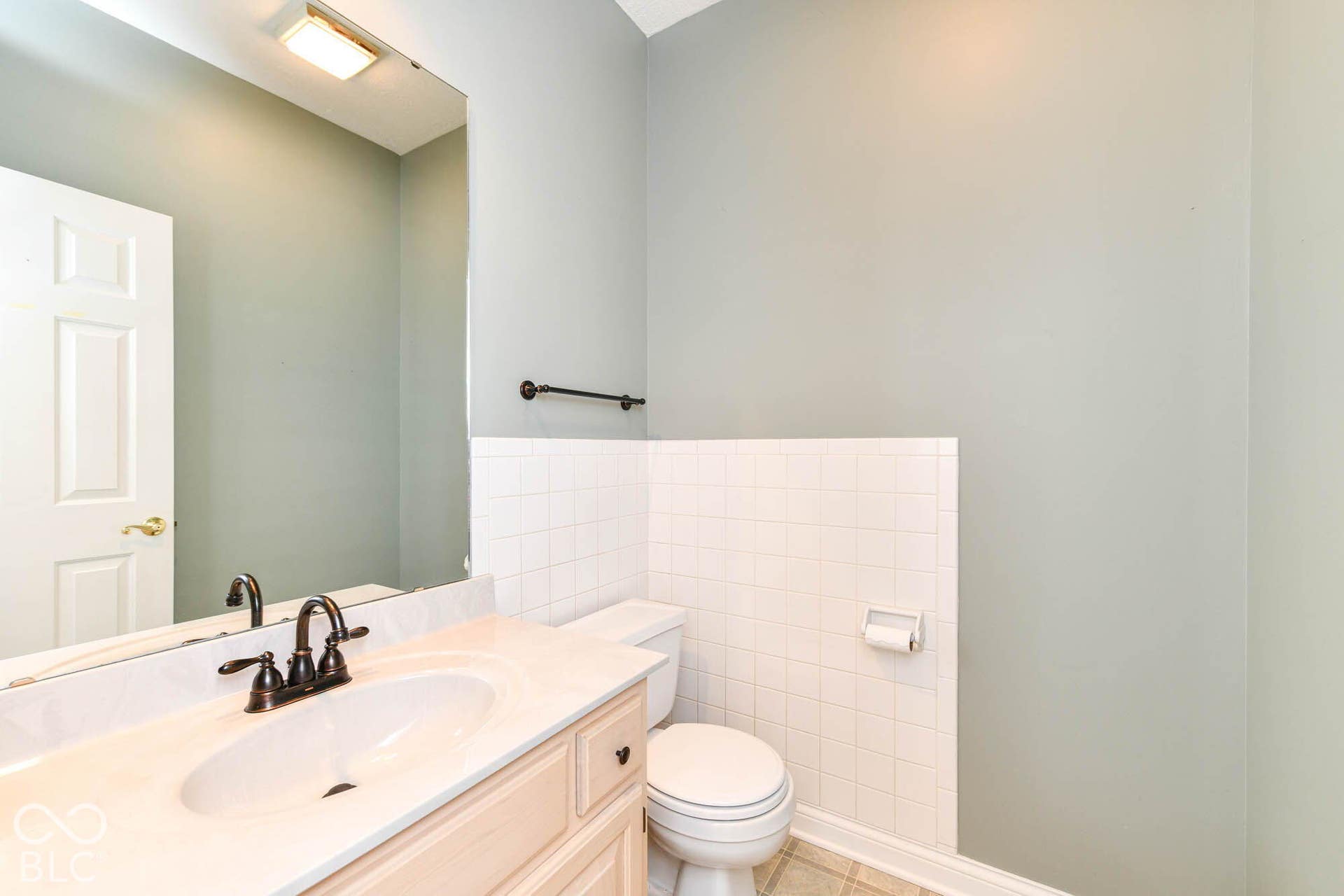 6431 Shamel Drive, Indianapolis, IN 46278 Half Bath on main level. Vanity with integrated sink and bronze-finish faucet, full-width wall mirror, and white tile wainscoting