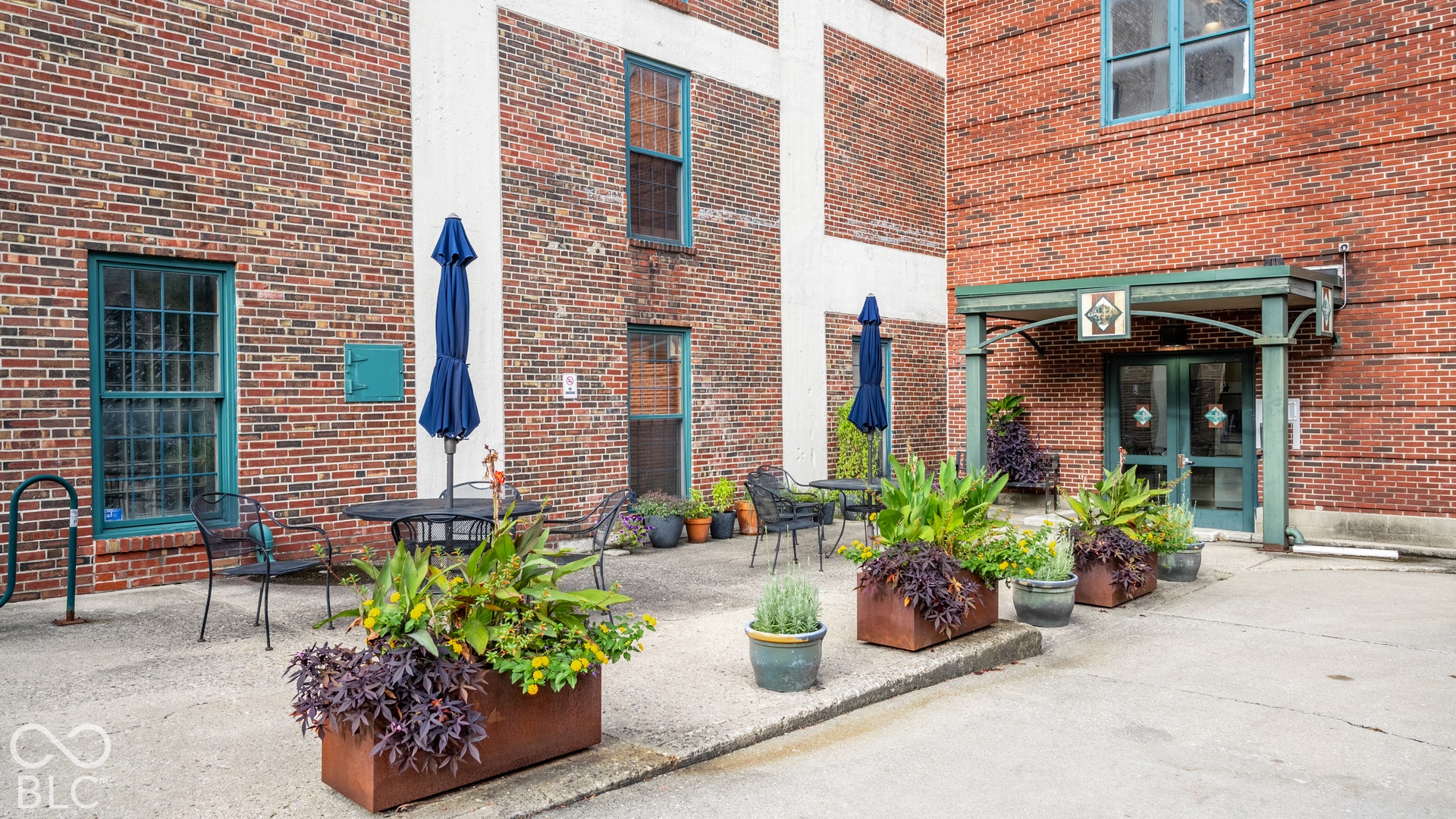 Brick exterior featuring an entryway with an awning, glass-paneled doors, and multiple decorative planters