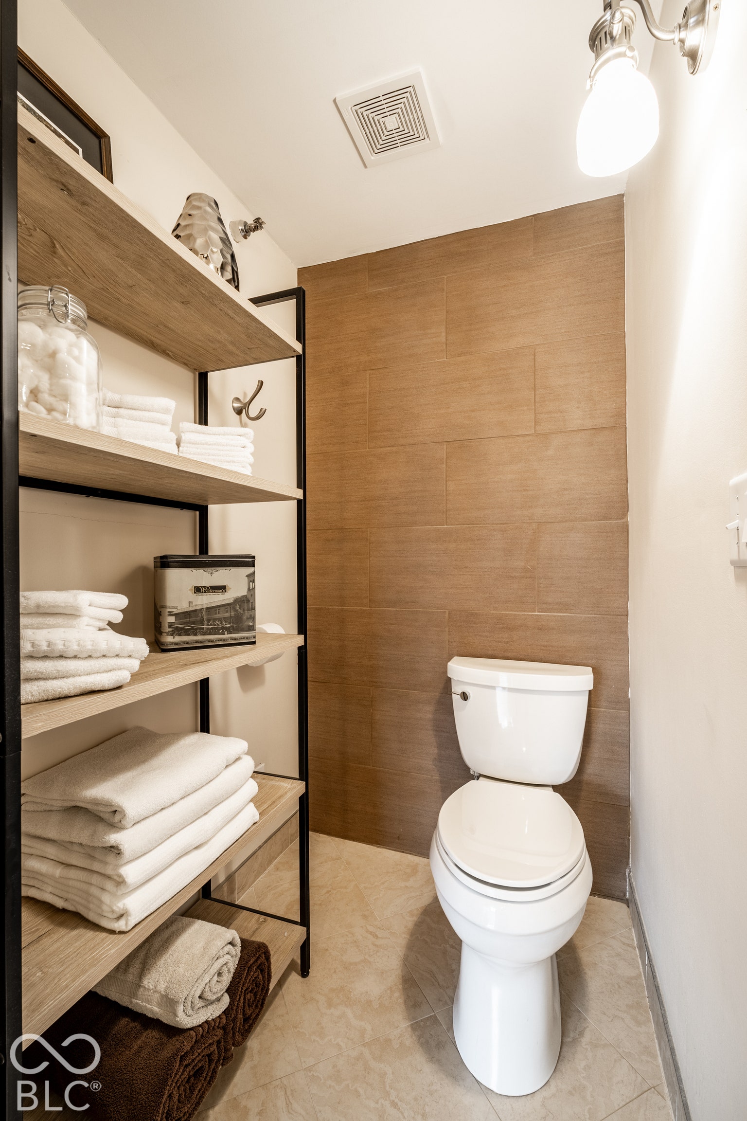 Floor-mounted toilet with a tiled accent wall and tiled flooring